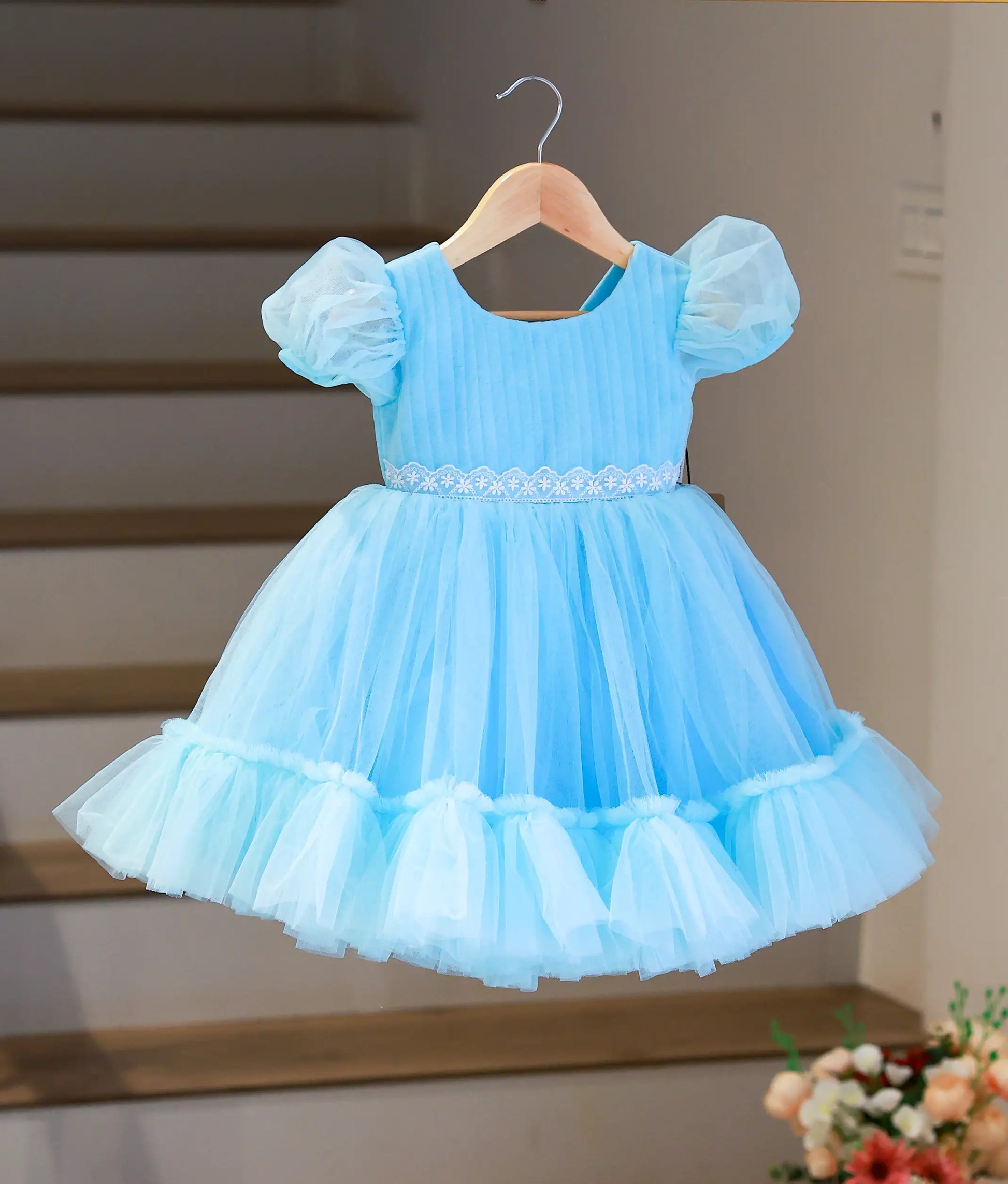 Full front view of a sky blue below-knee party frock for girls featuring a pleated bodice and ruffled tulle skirt.