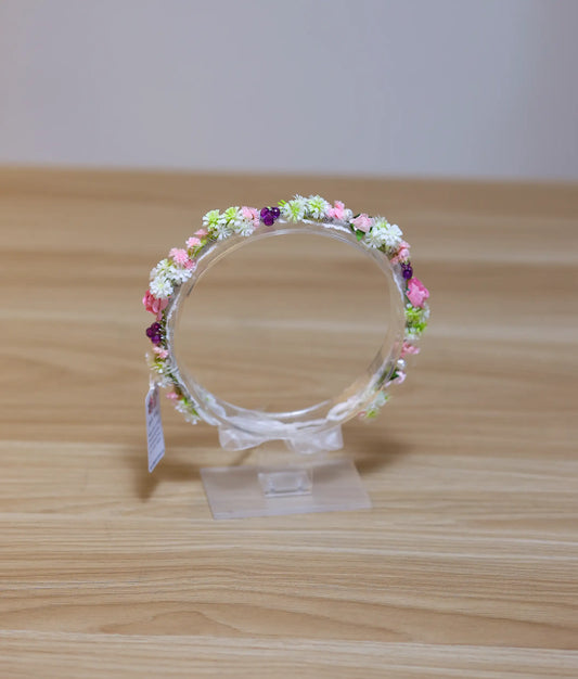 Front view of a soft pink and white floral handmade tiara for girls on a flexible white band