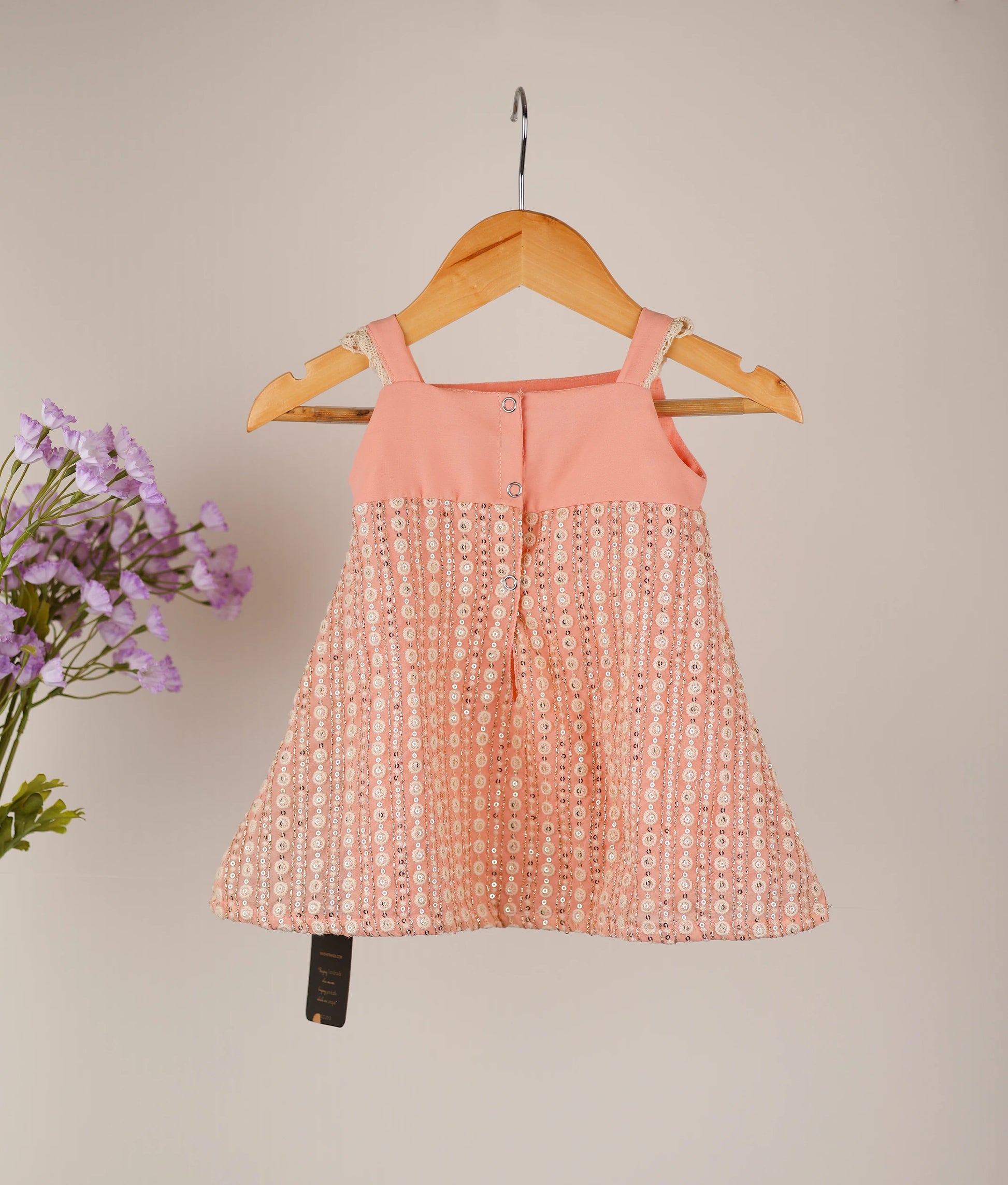 Back view of the peach A-line frock highlighting the square neck and press button closure