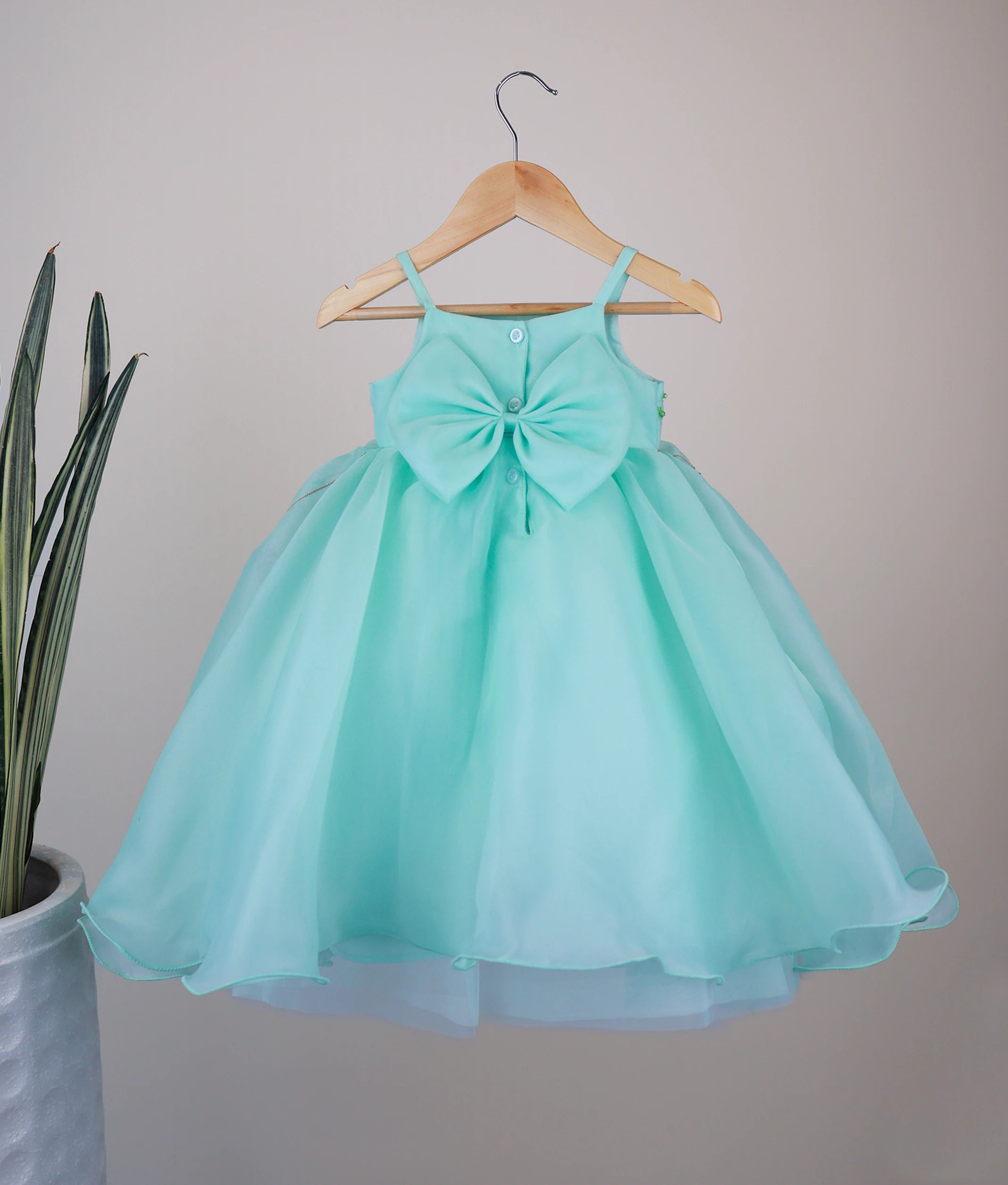 Back view of the ocean green luxe gown highlighting the square neckline and show button closure