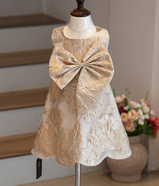 Front view of a cream and gold Turkish organza A-line frock with a front bow.