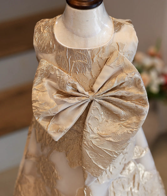 Close-up of the textured gold leaf pattern and large bow on the Turkish organza frock.