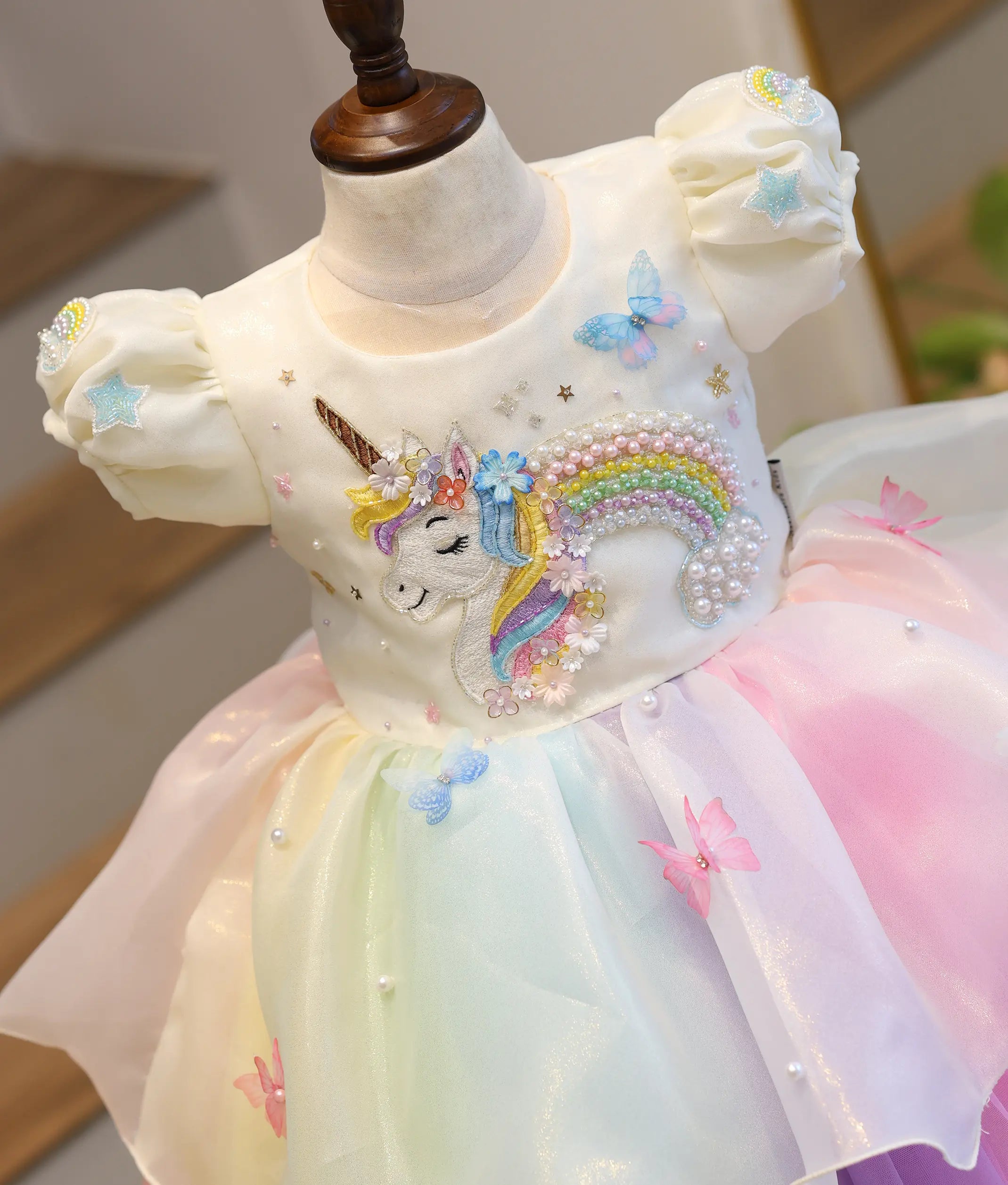 Close-up of the front bodice detailing the hand-worked multi-colored unicorn applique with stars, pearls, and tiny 3D butterfly details.