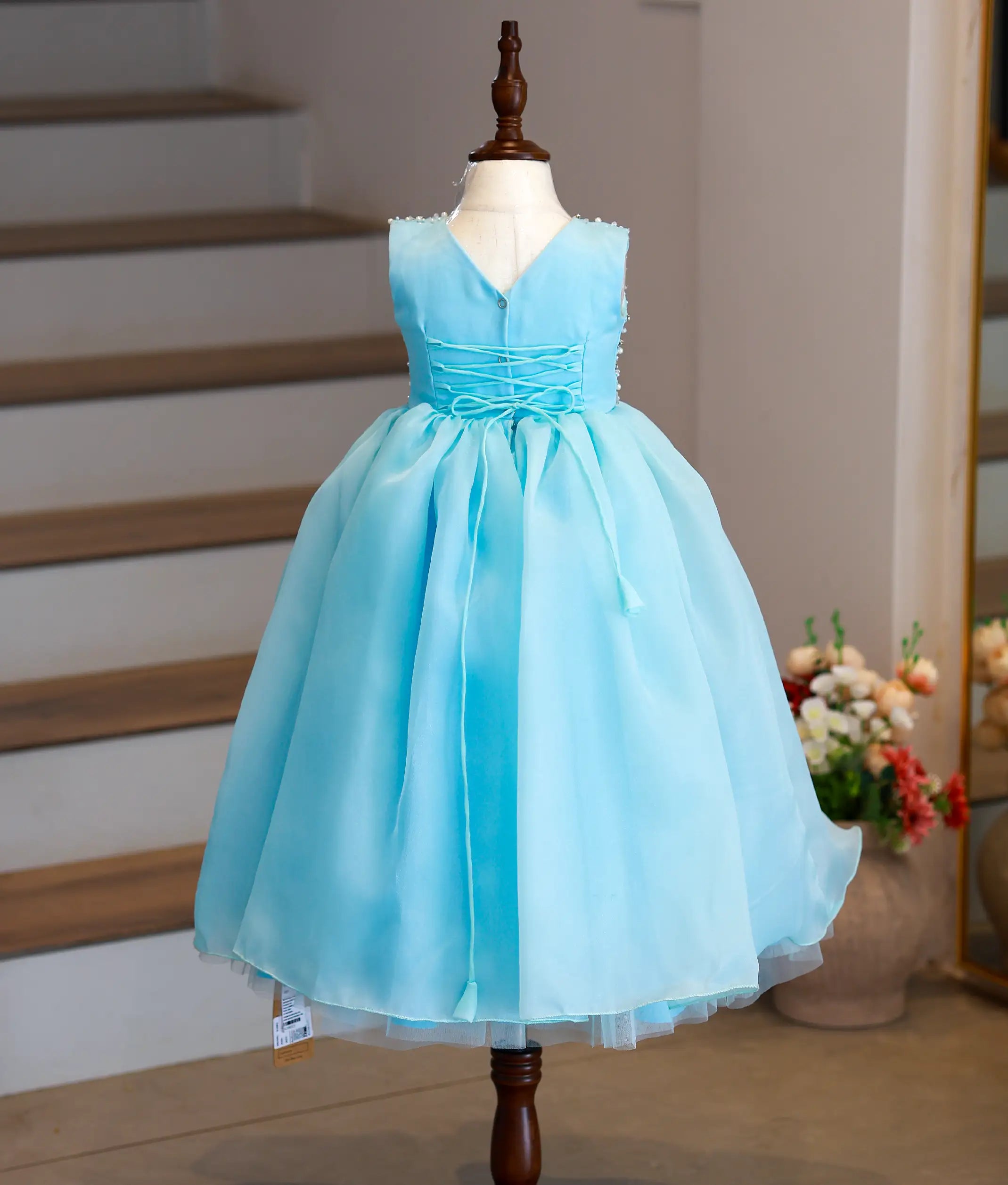Back view of the sky blue organza gown highlighting the elegant V-neckline and button closure