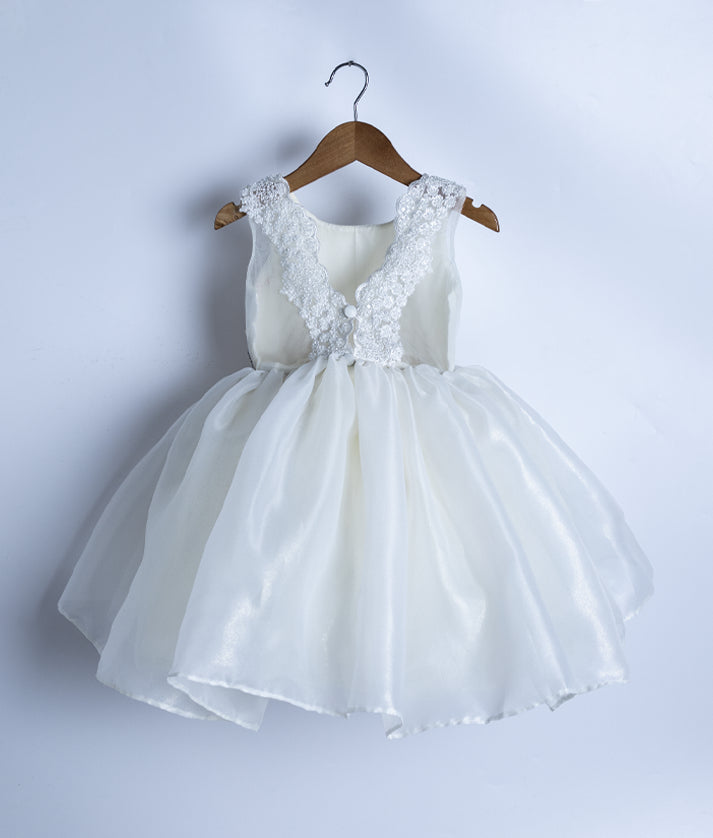 Back view of the off-white birthday frock highlighting the lace-bordered V-neckline and decorative buttons