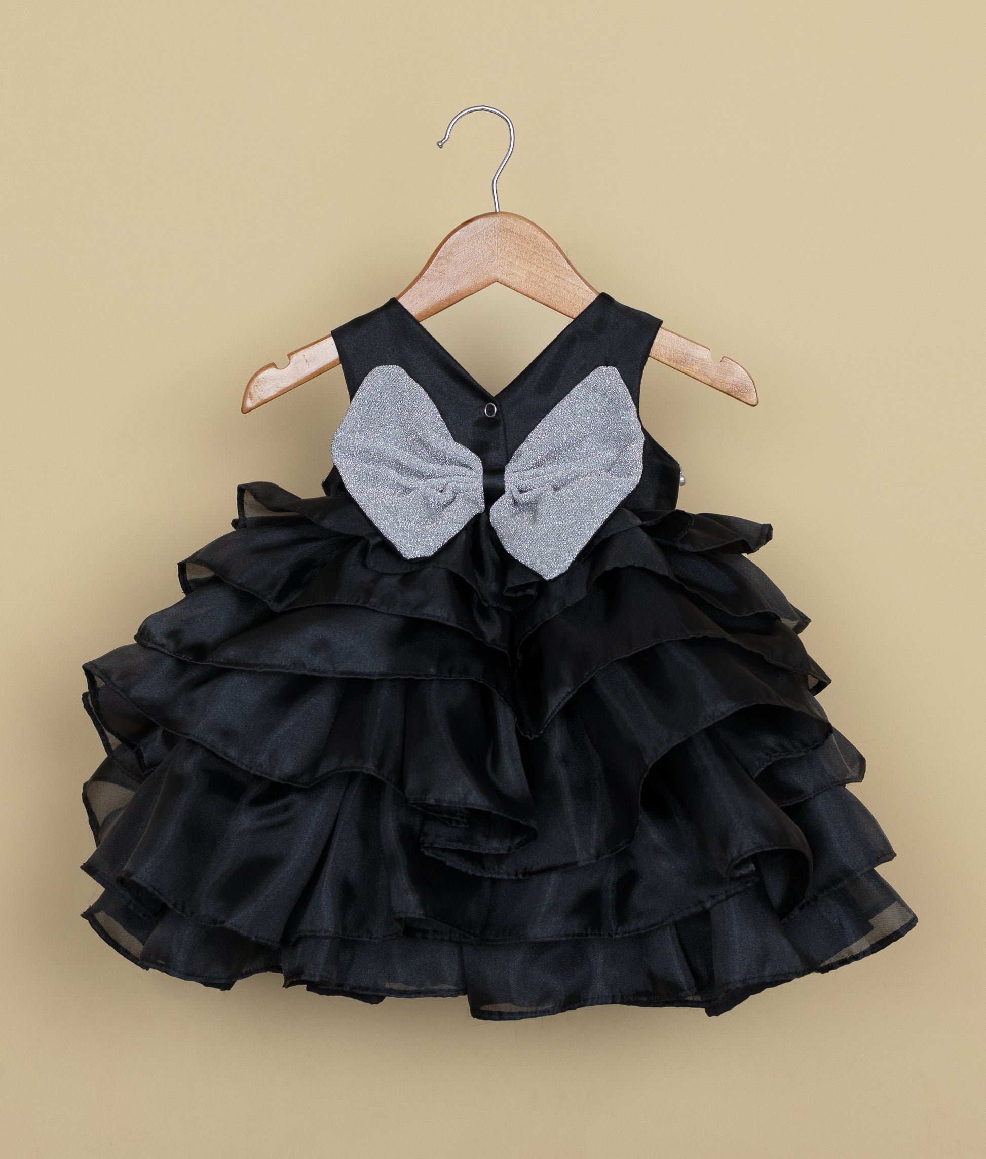 Back view of the black organza frock featuring a V-neckline, press button closure, and a decorative silver bow