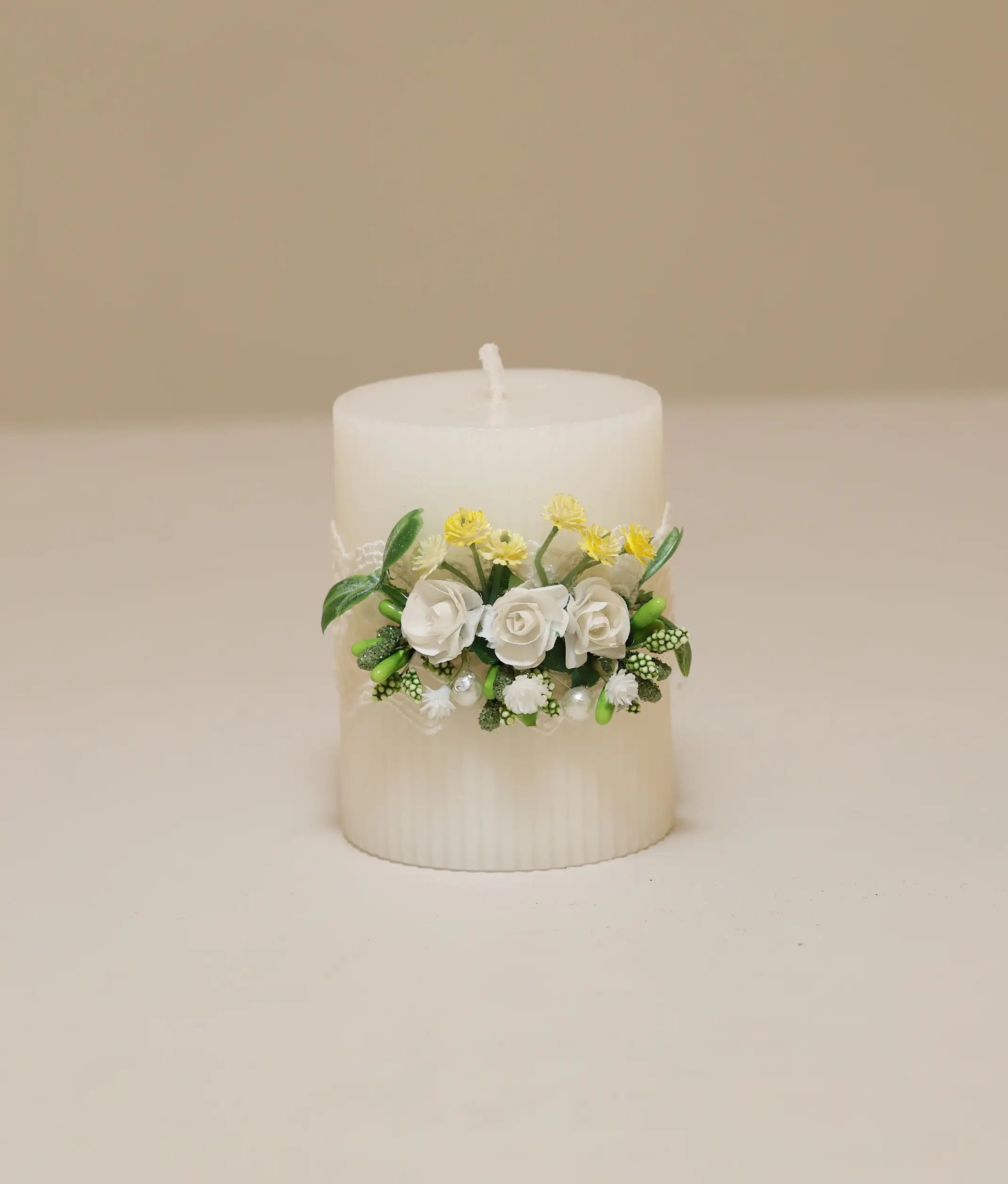 White pillar baptism candle decorated with yellow silk flowers, white lace ruffles, and gold pearl accents