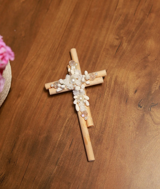 Close-up of the white handcrafted flowers, shimmering pearls, and textured detail on the baptism cross