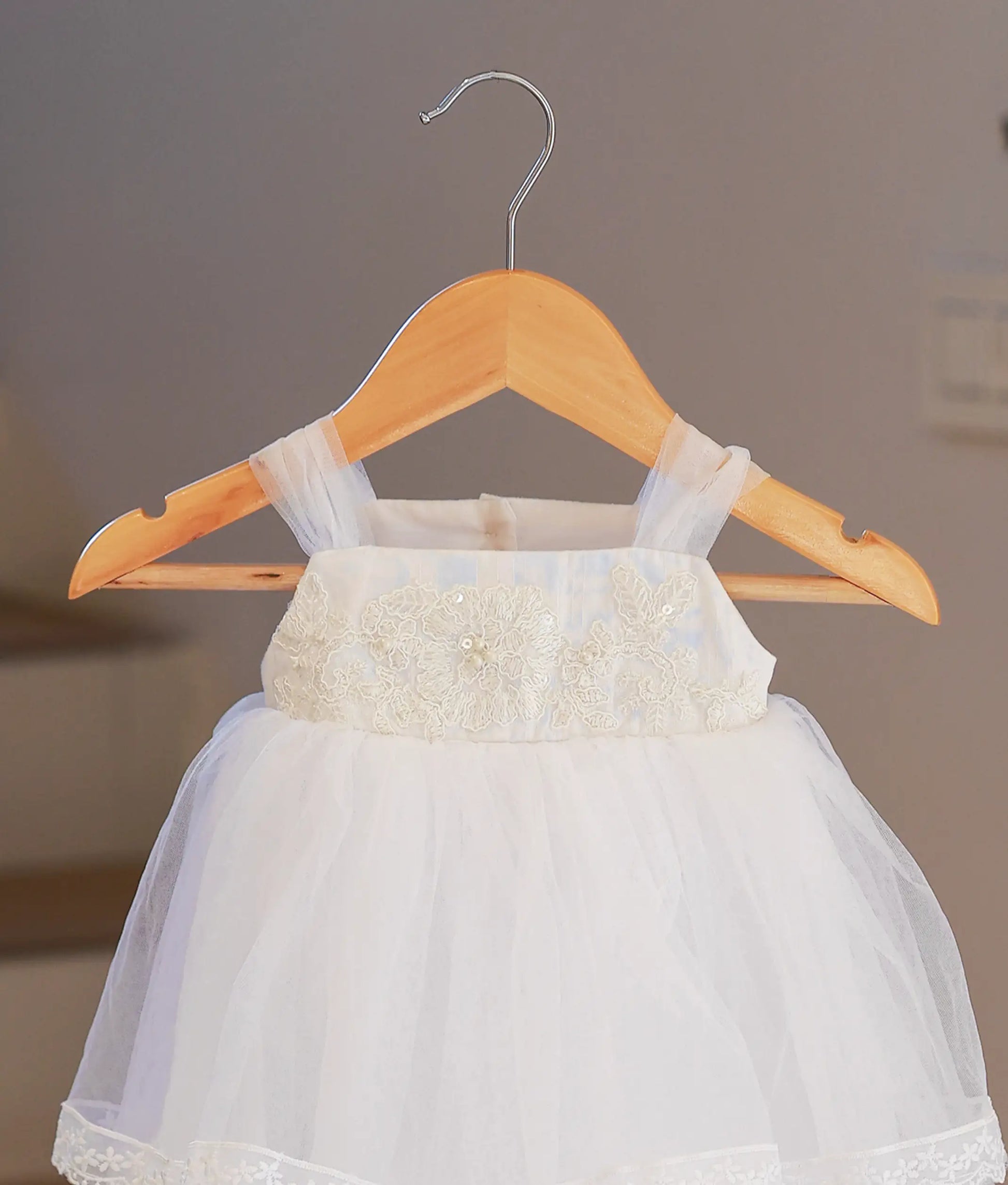 Close-up of the white baptism frock highlighting the intricate floral embroidery and the soft texture of the tulle net fabric.