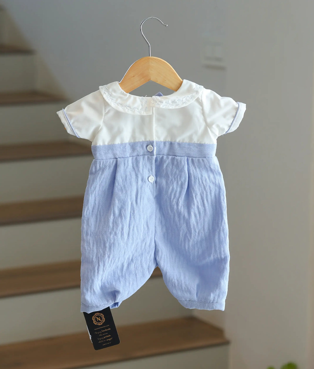 Back view of the white and blue baptism romper showing the button fasteners.