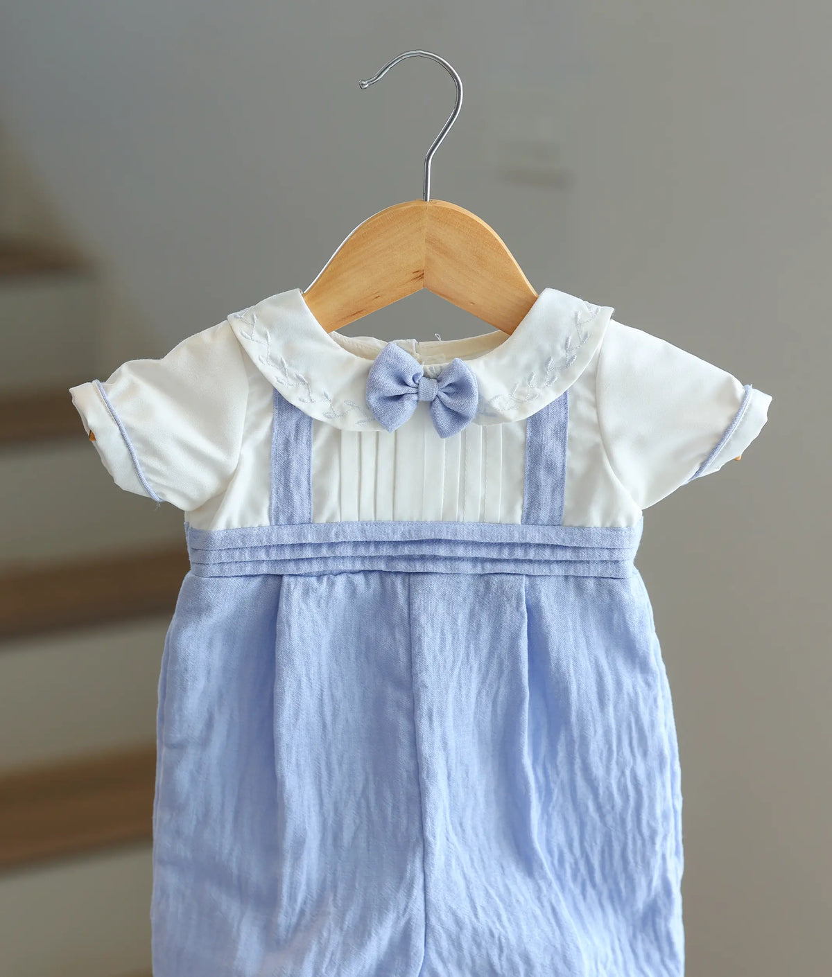 Close-up of the white bodice showing the light blue bow tie and embroidered Peter Pan collar.