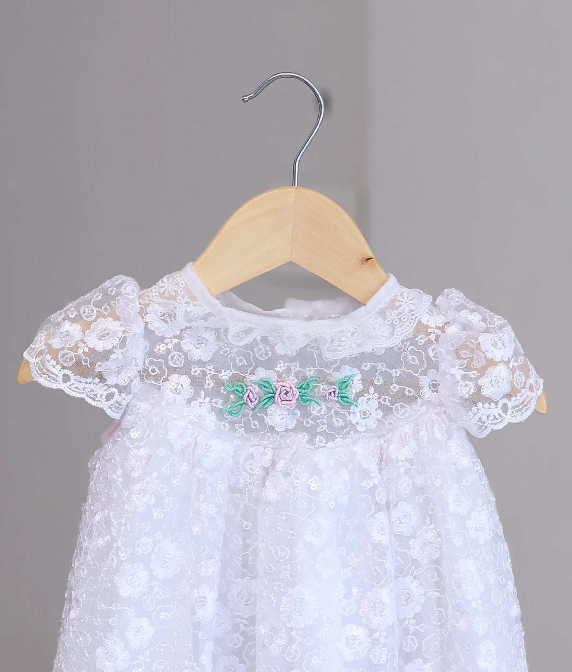 Close-up of premium hand-stitched pearls and soft white lace on a boutique handcrafted christening dress