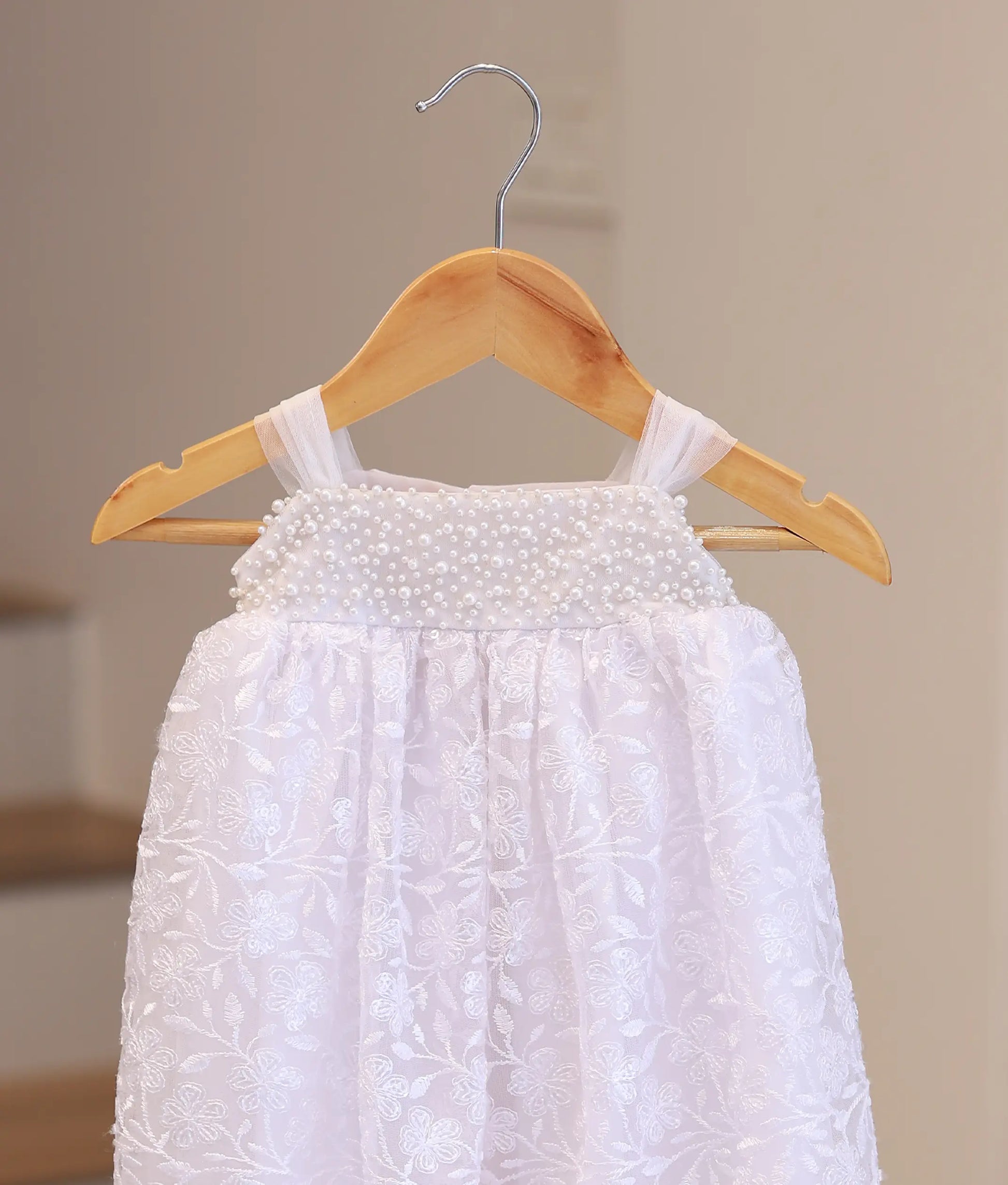 Close-up of premium hand-stitched pearls and soft white lace on a boutique handcrafted christening dress