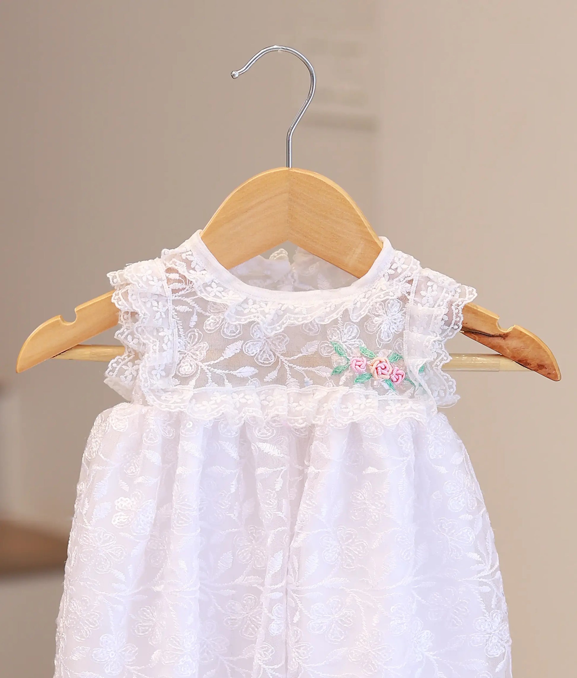 Close-up of premium hand-stitched pearls and intricate white lace on a boutique baby christening dress