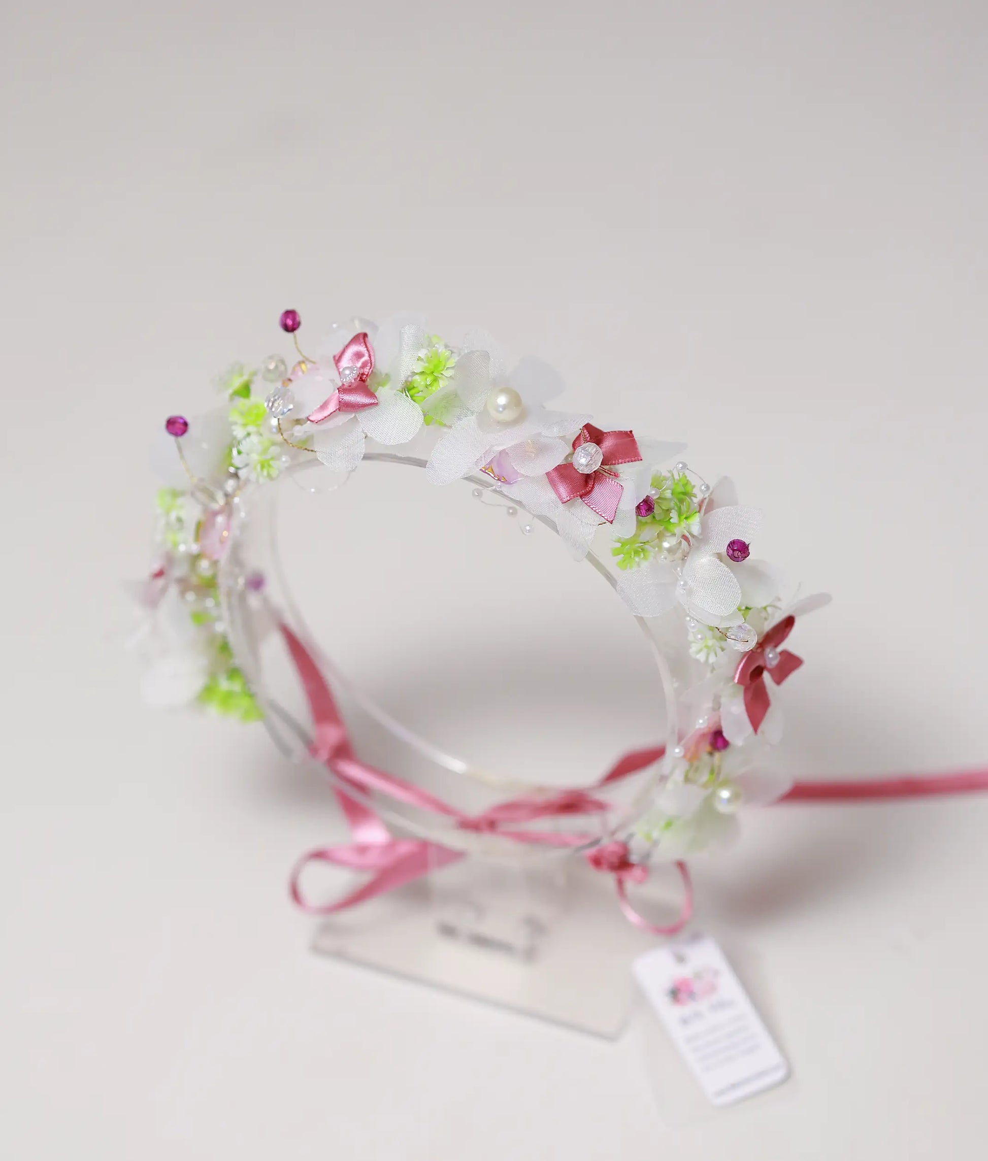 Front view of a white and pink blossom handmade tiara for girls with pearls and a pink ribbon tie