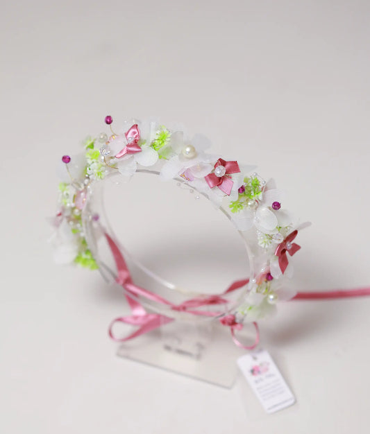 Front view of a white and pink blossom handmade tiara for girls with pearls and a pink ribbon tie