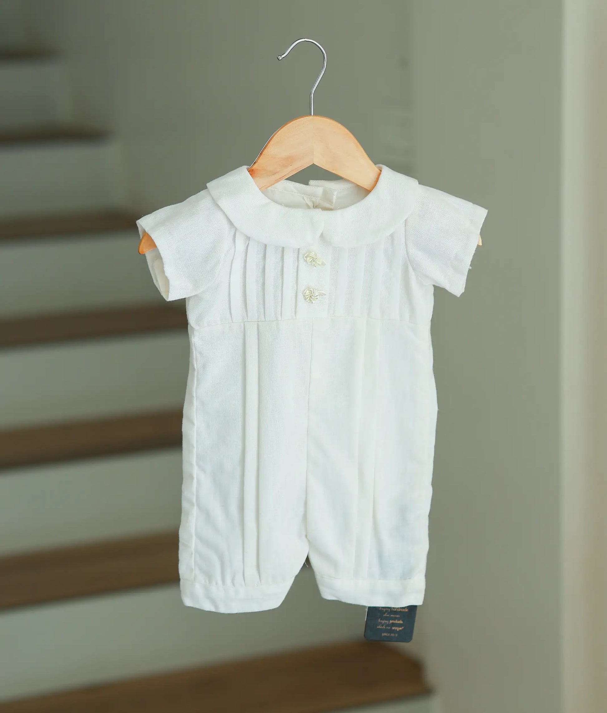 Front full view of an off-white cotton baptism romper for baby boys featuring vertical pleats and a Peter Pan collar