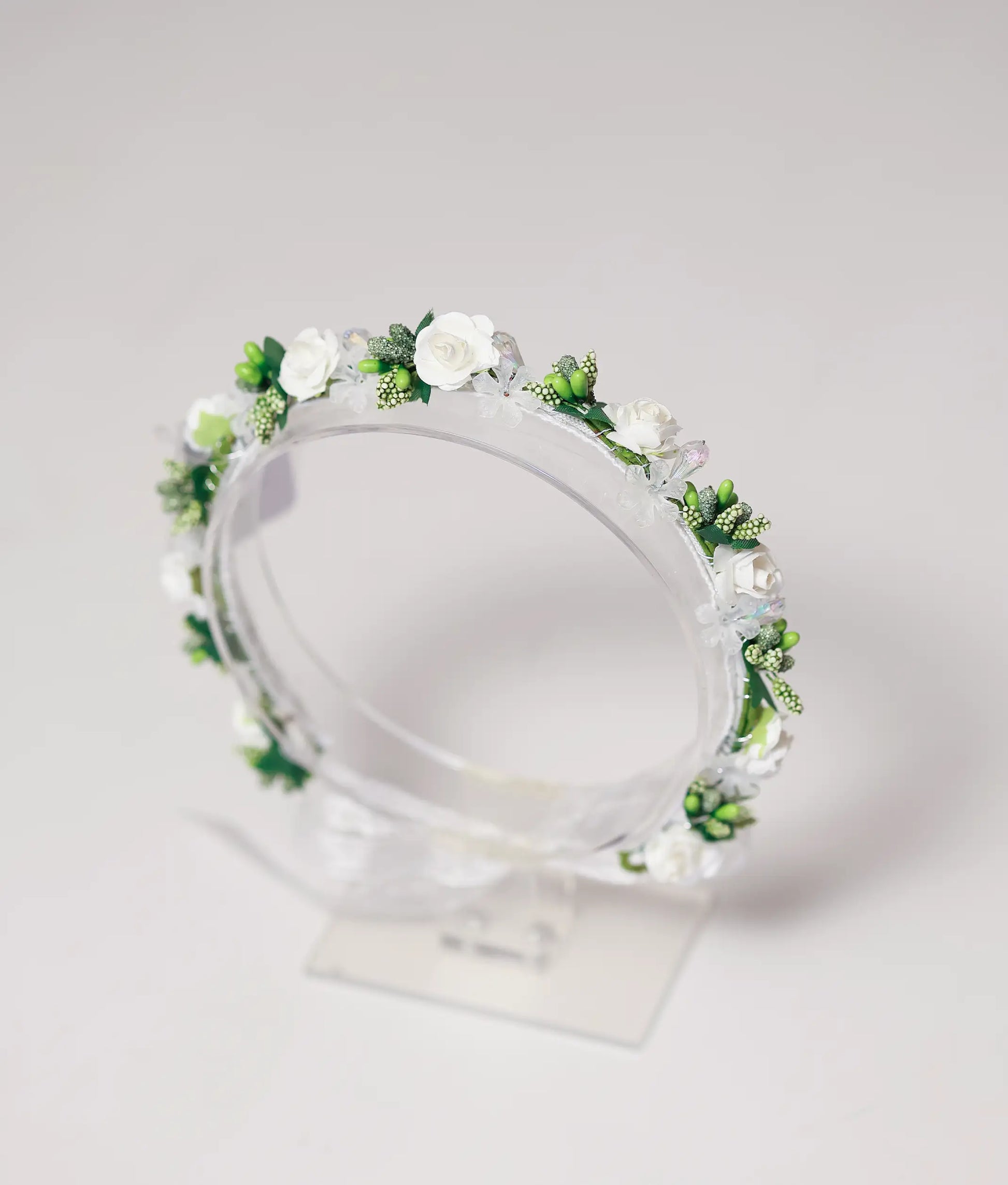 Close-up of the handmade tiara showing detailed white roses, green bud clusters, and shimmering crystal beads