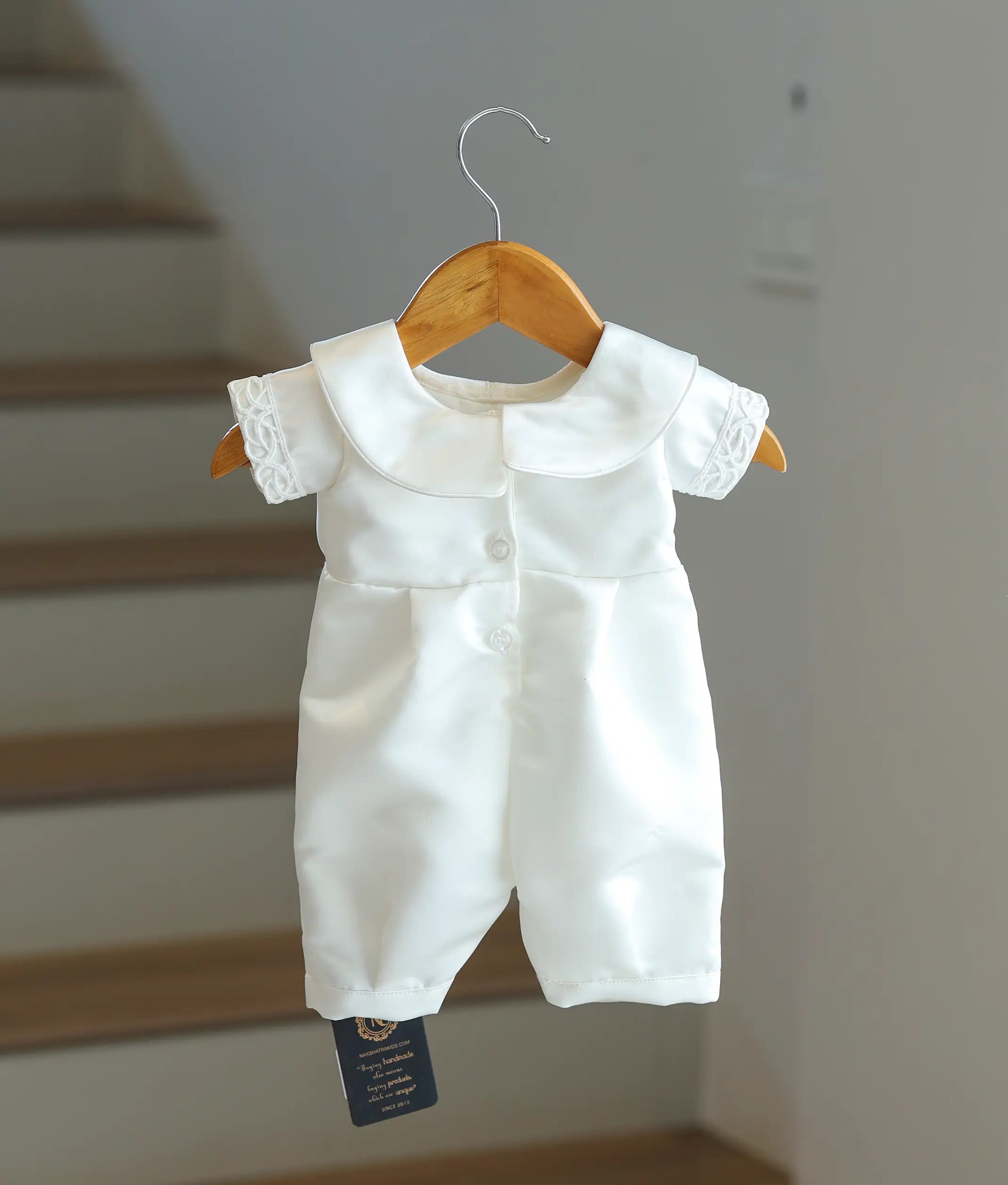 Back view of the white satin baptism romper showing the button fasteners.