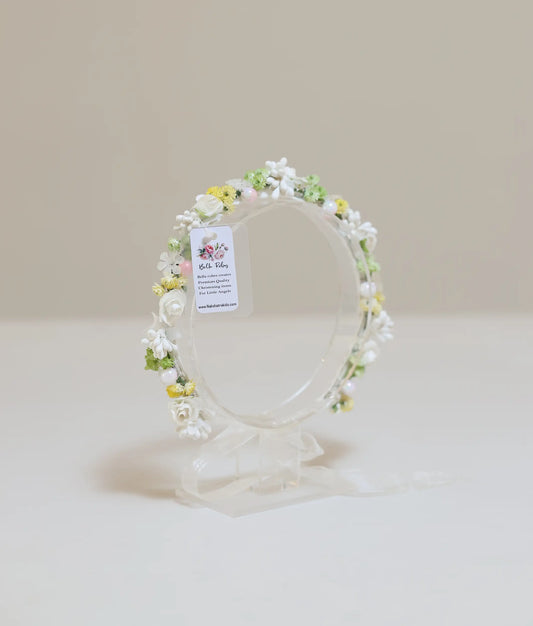 Front view of a white and yellow floral handmade tiara for girls with pearls and ribbon tie