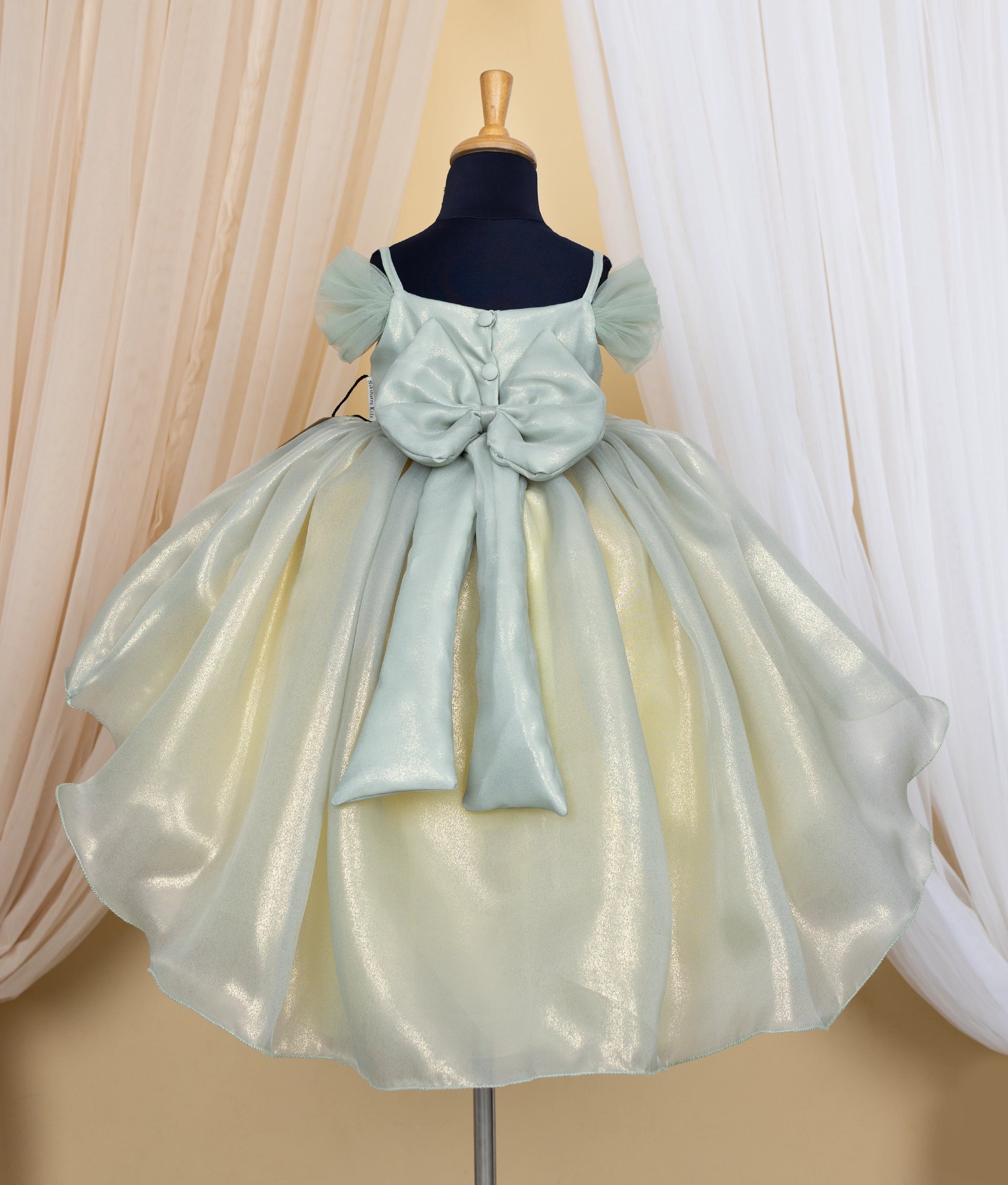 Back view of an pastel green and yellow frock displayed on mannequin.