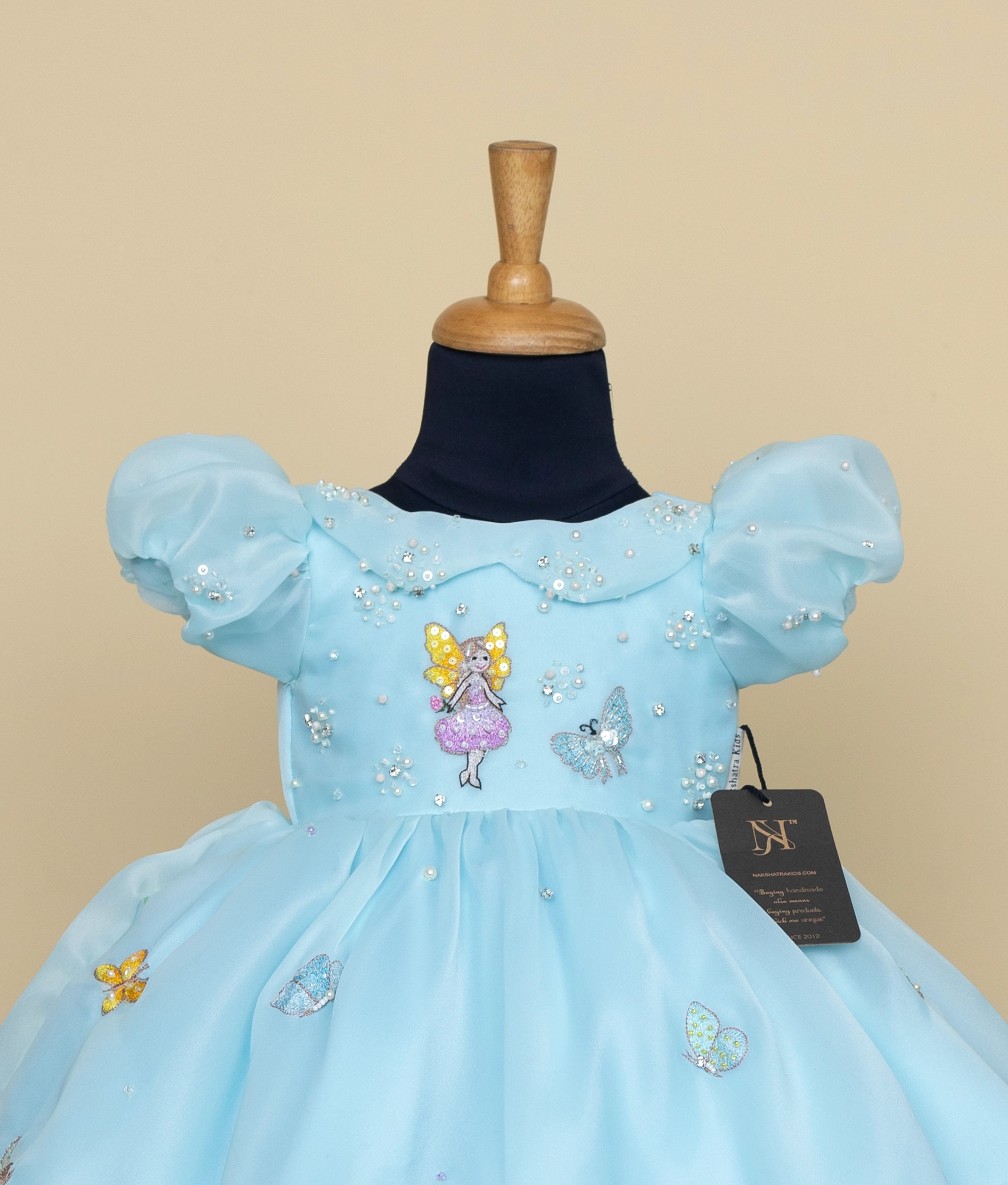 A close view of blue princess dress for girls with fairy tale embroidery, puff sleeves, and pearl embellishments.
