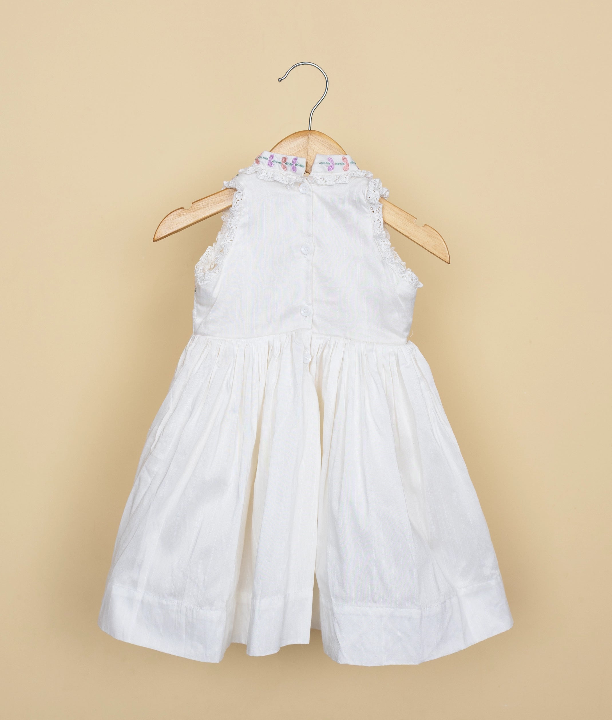 Back side of a White dress with floral details on a beige background