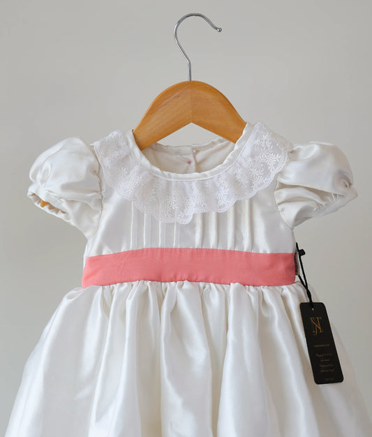 Close view of an off-white Satin Organza Baptism Frock against a plain background.  