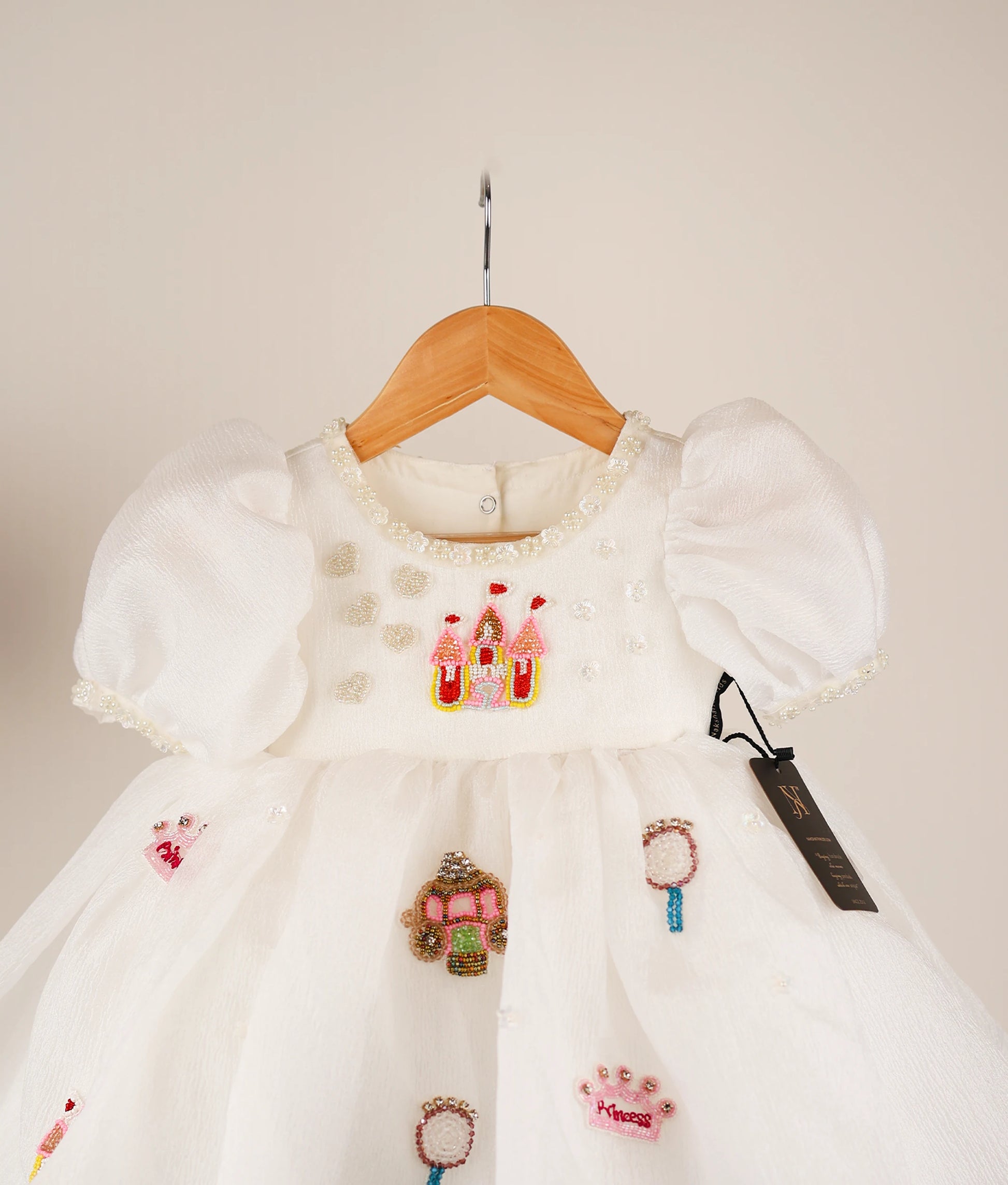 Close view of an off-white princess-themed dress against white background