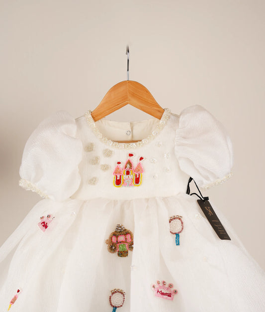Close view of an off-white princess-themed dress against white background