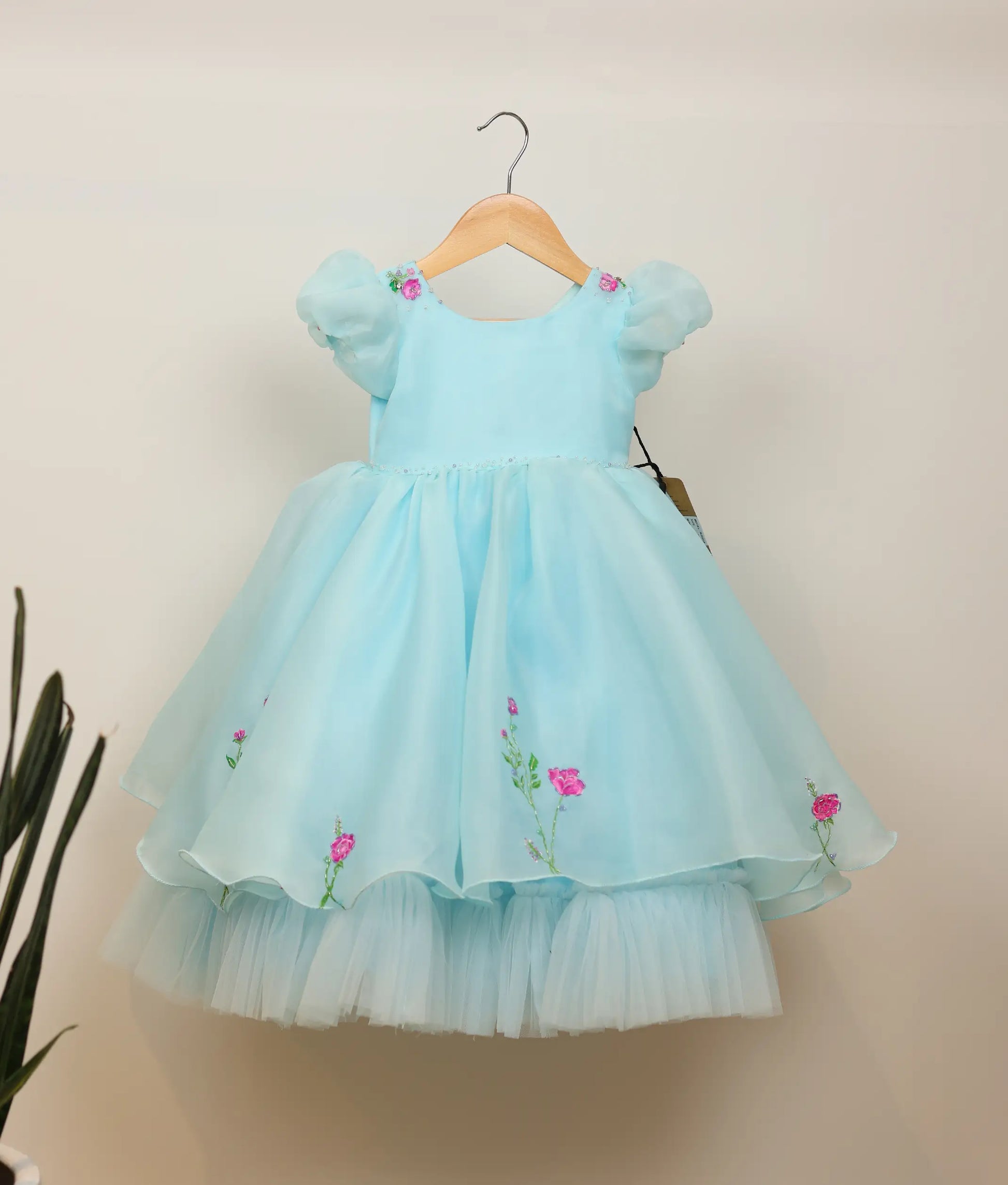 Front view of sky blue plain organza floral painting and handworked birthday gown against plain background