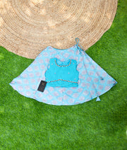 Sky blue handwork top with peach skirt laid out on a green surface, traditional wear.