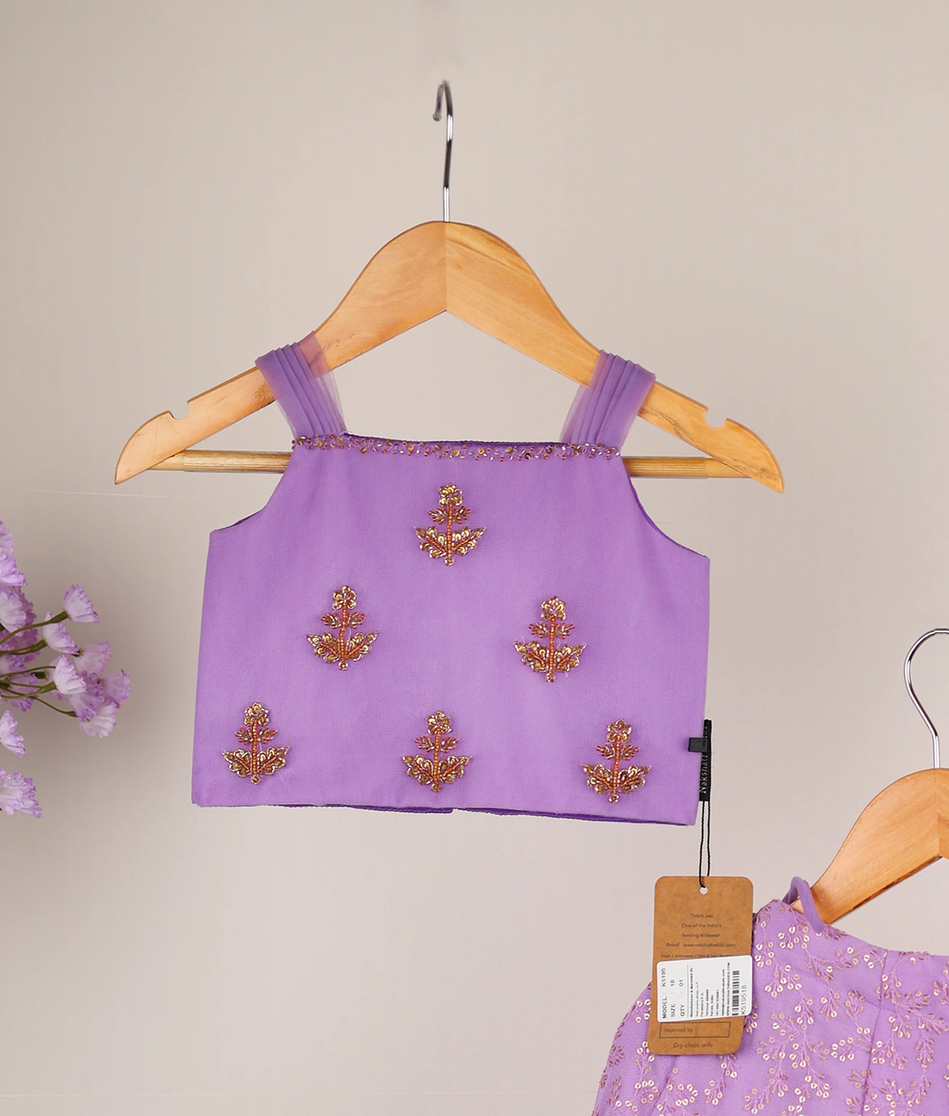 Close view of lavender handworked top and georgette skirt against plain background.