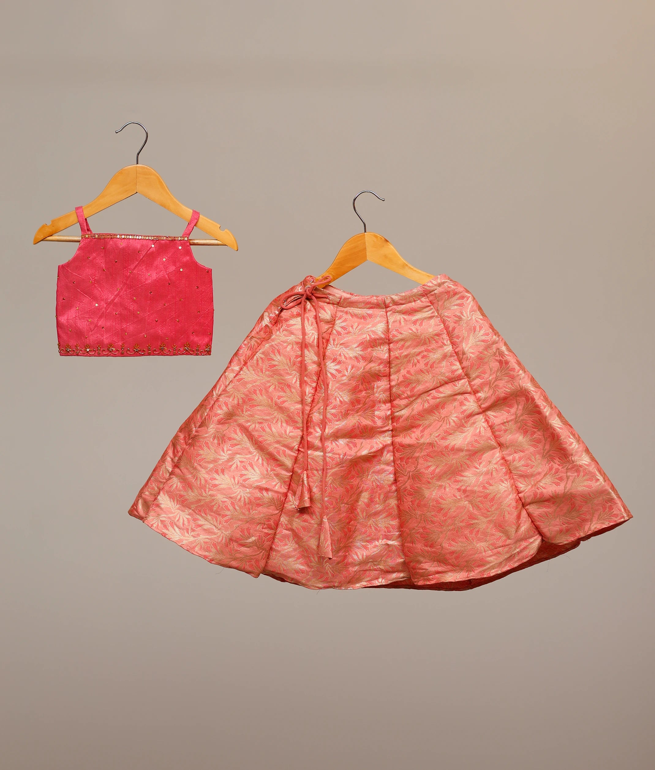 Kids' hot-pink lehenga choli set with a handwork-embellished top and a floral banarasi skirt.
