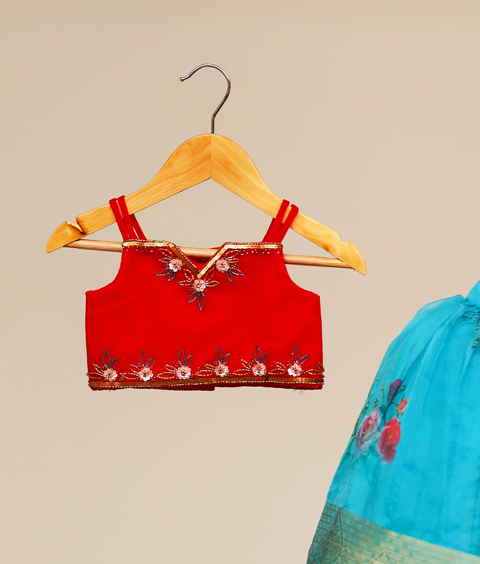 Close view of a red tulle net top for kids with golden handwork. Blue floral Printed organza skirt. 