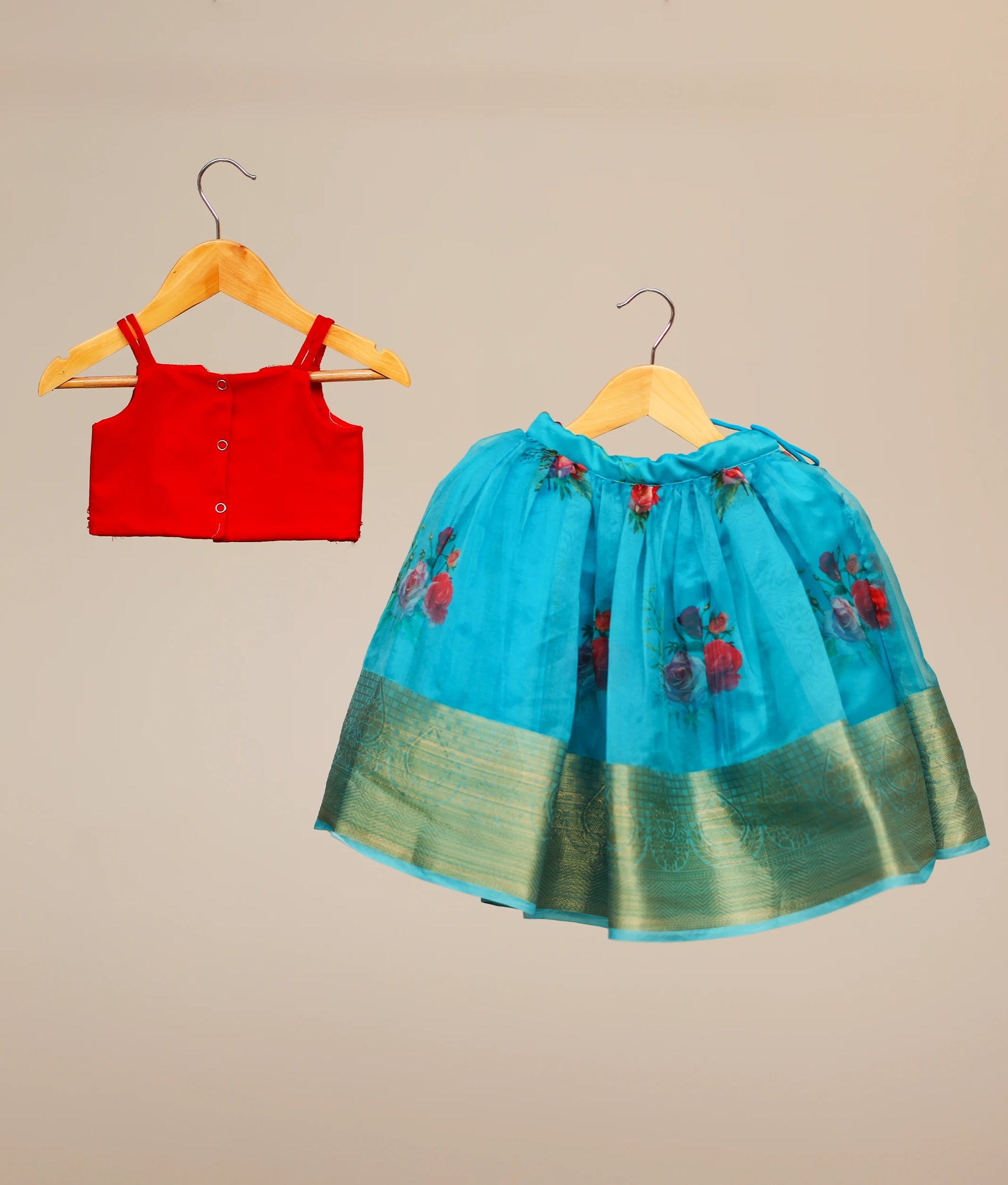 Back view of a red tulle net top for kids with golden handwork. Blue floral Printed organza skirt. 