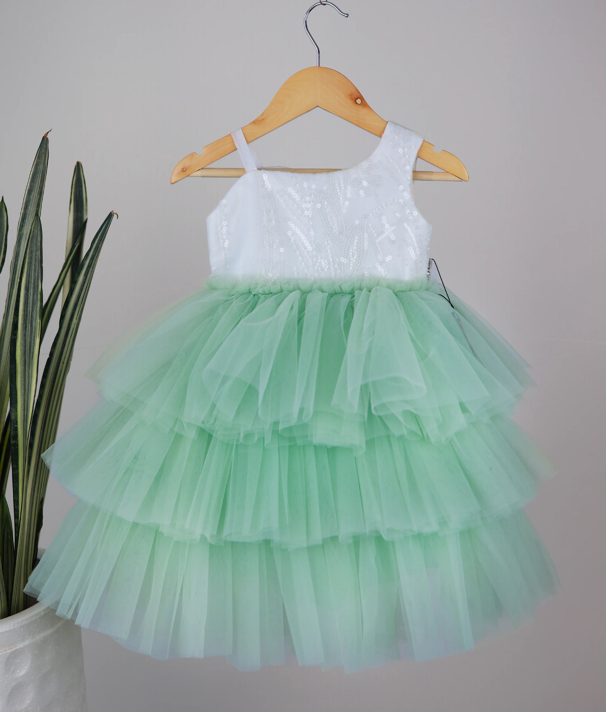 Front view of an off-white work material yoke with pastel green birthday frock with white background