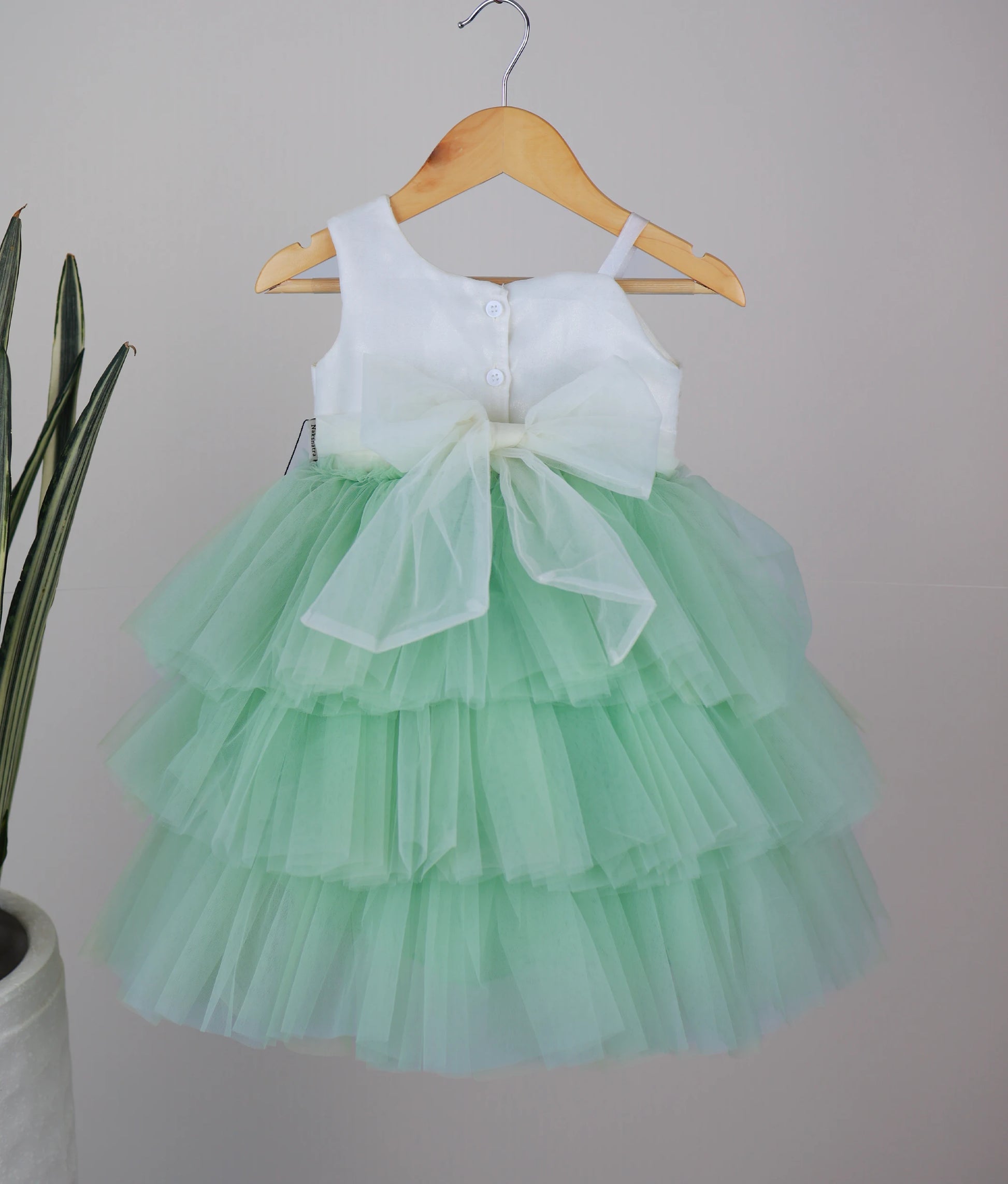 Back view of an off-white work material yoke with pastel green birthday frock with white background