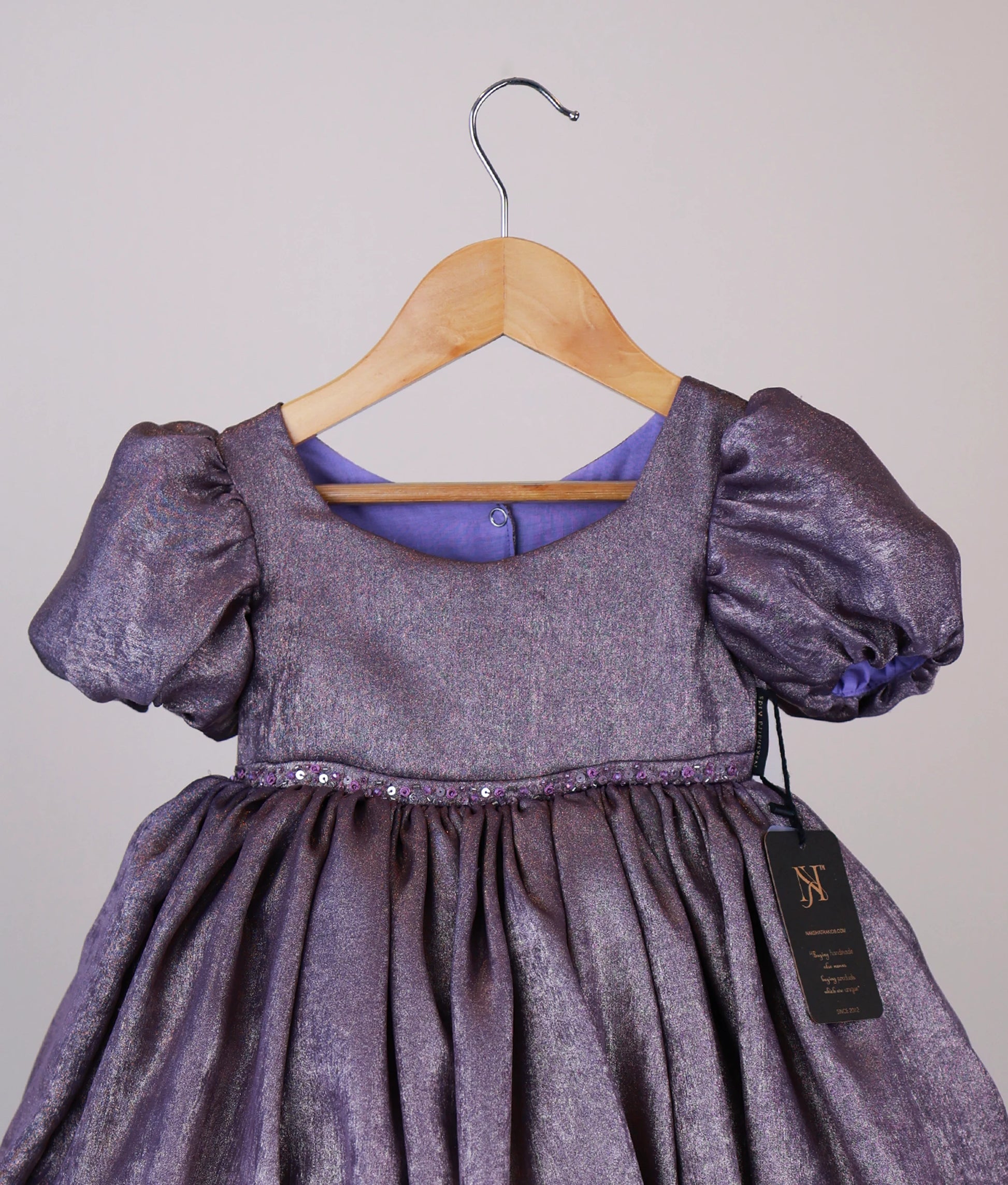Close view of an handworked milan foil frock against white background