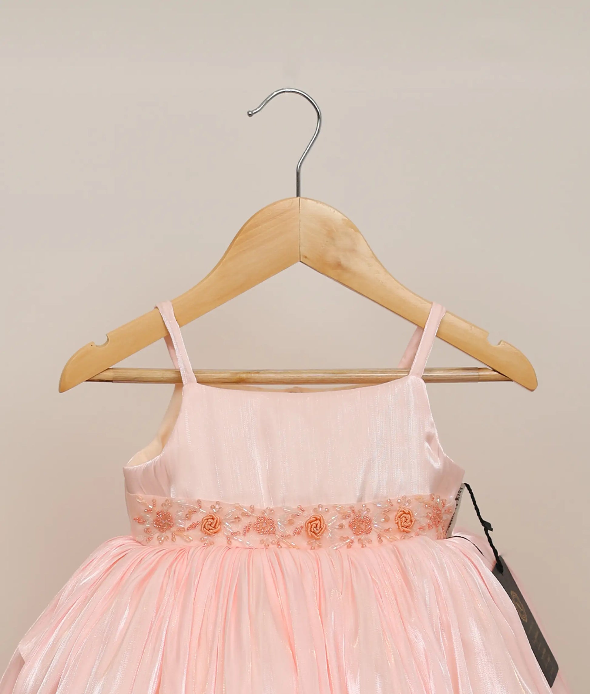 Close view of a pink lacer organza hand-worked birthday frock against plain background