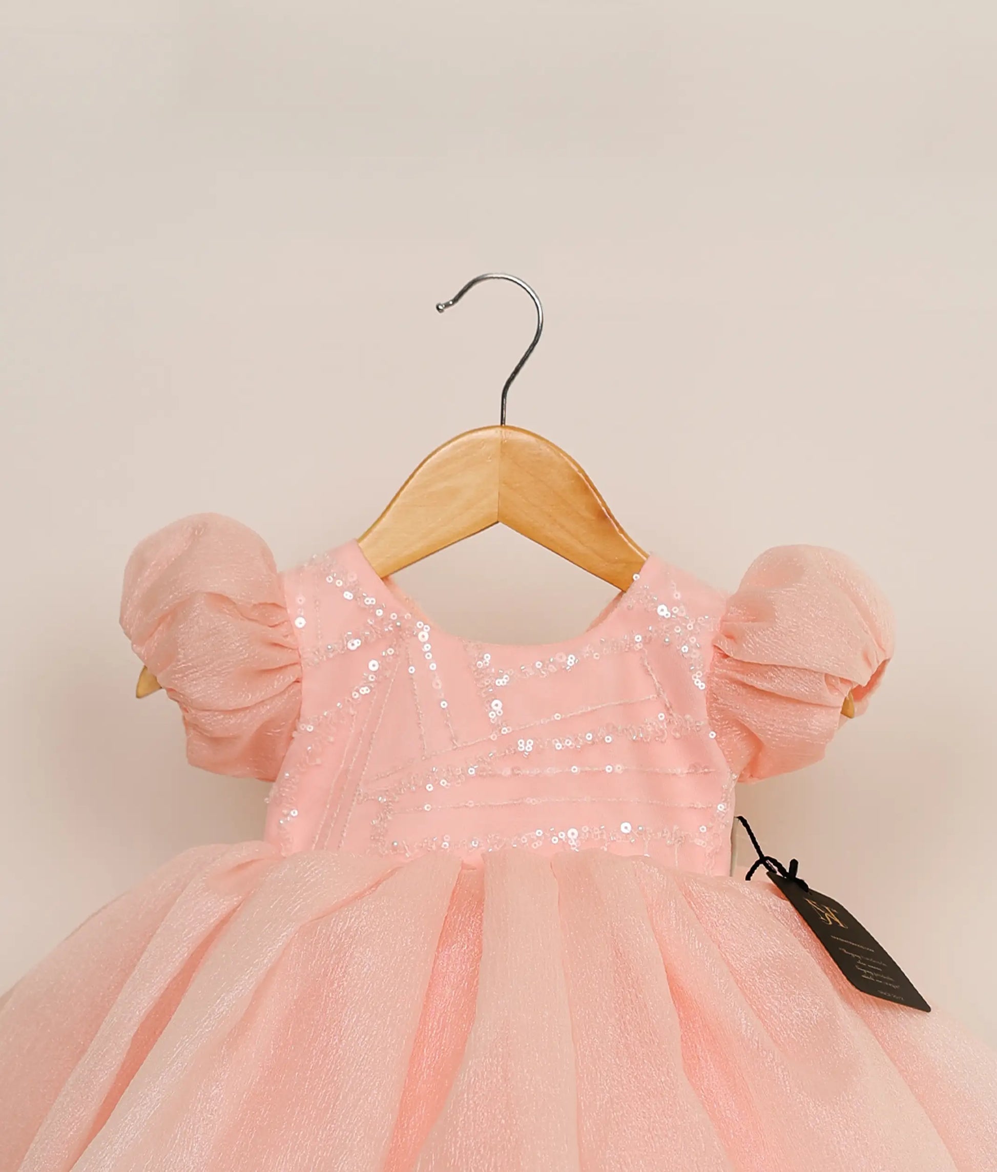 Close view of a pastel pink crush organza birthday frock against plain background