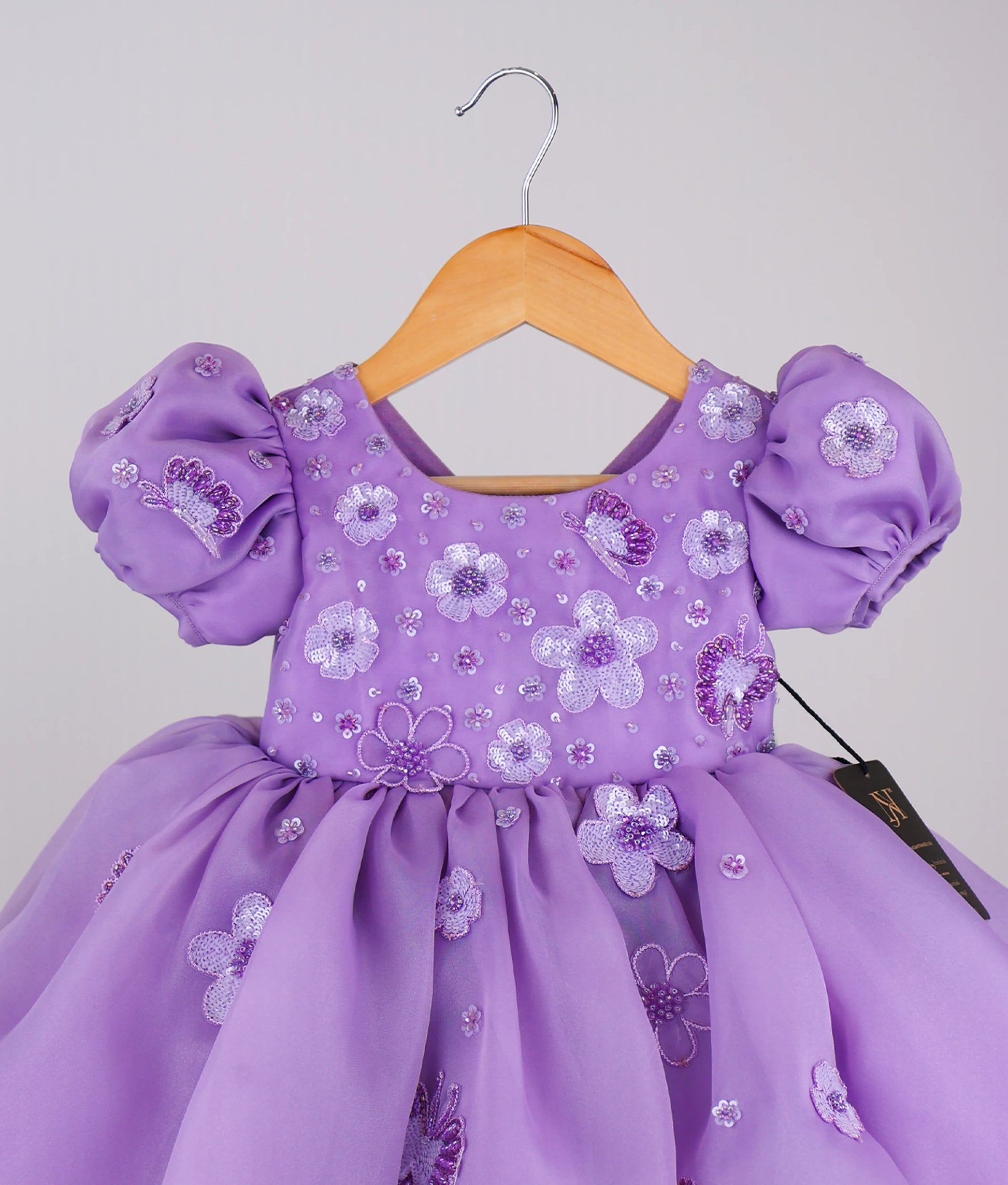 Close view of handworked flower-themed baby girl dress against white background
