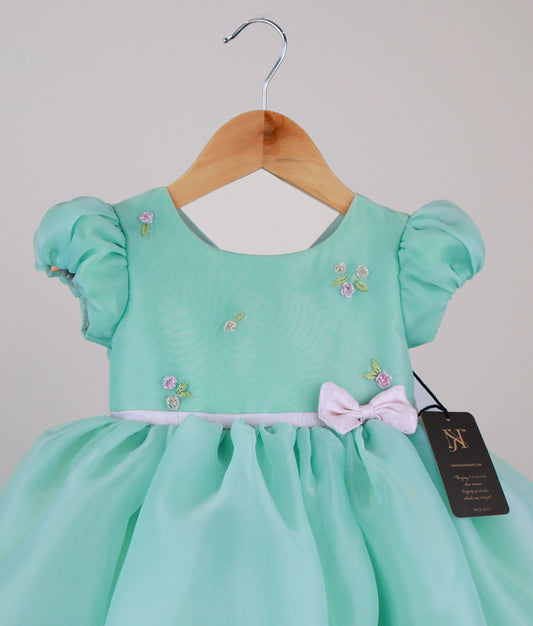 Close view of mint green organza baby dress with pink floral embroidery and handwork