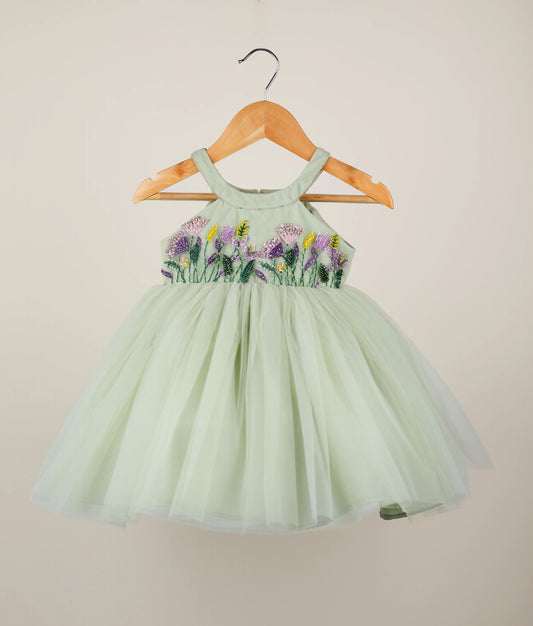 Front view of pastel green tulle net floral handworked birthday frock against plain background 