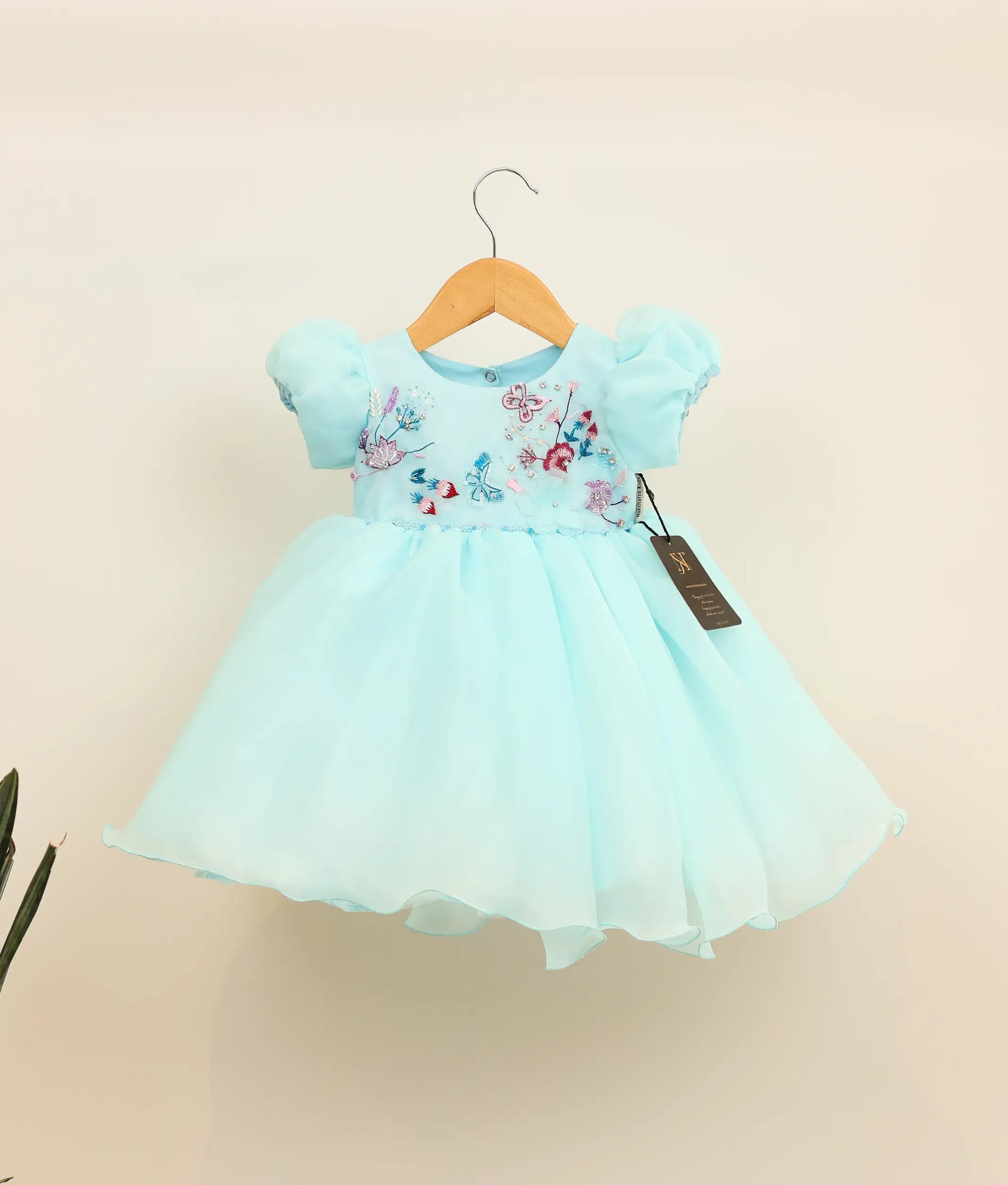 Front view of sky blue plain organza birthday frock aginst plain background