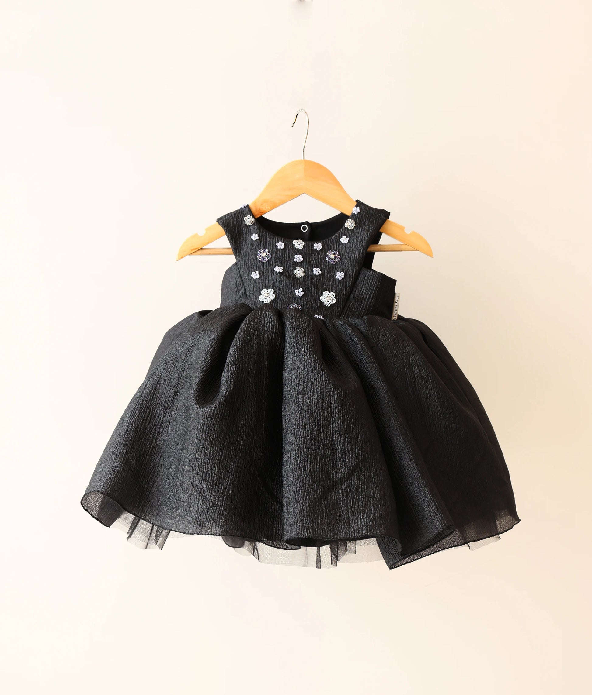 Front view of black crush organza floral handworked birthday frock against plain background