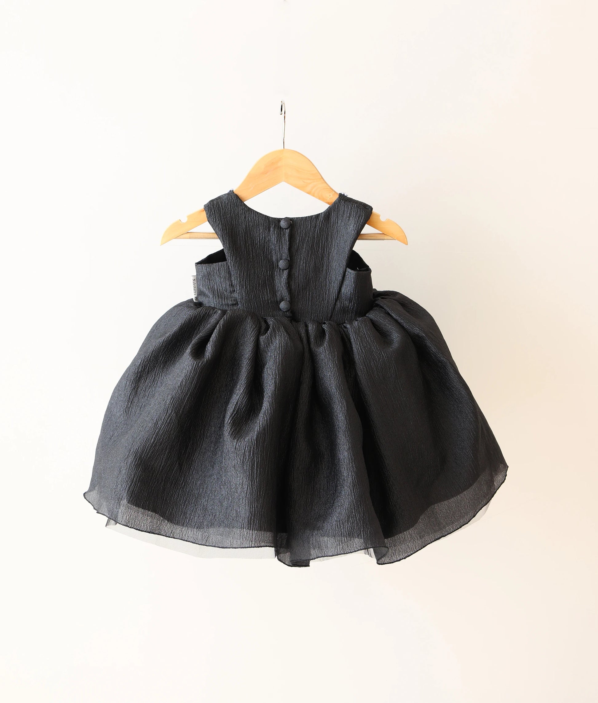 Back view of black crush organza floral handworked birthday frock against plain background