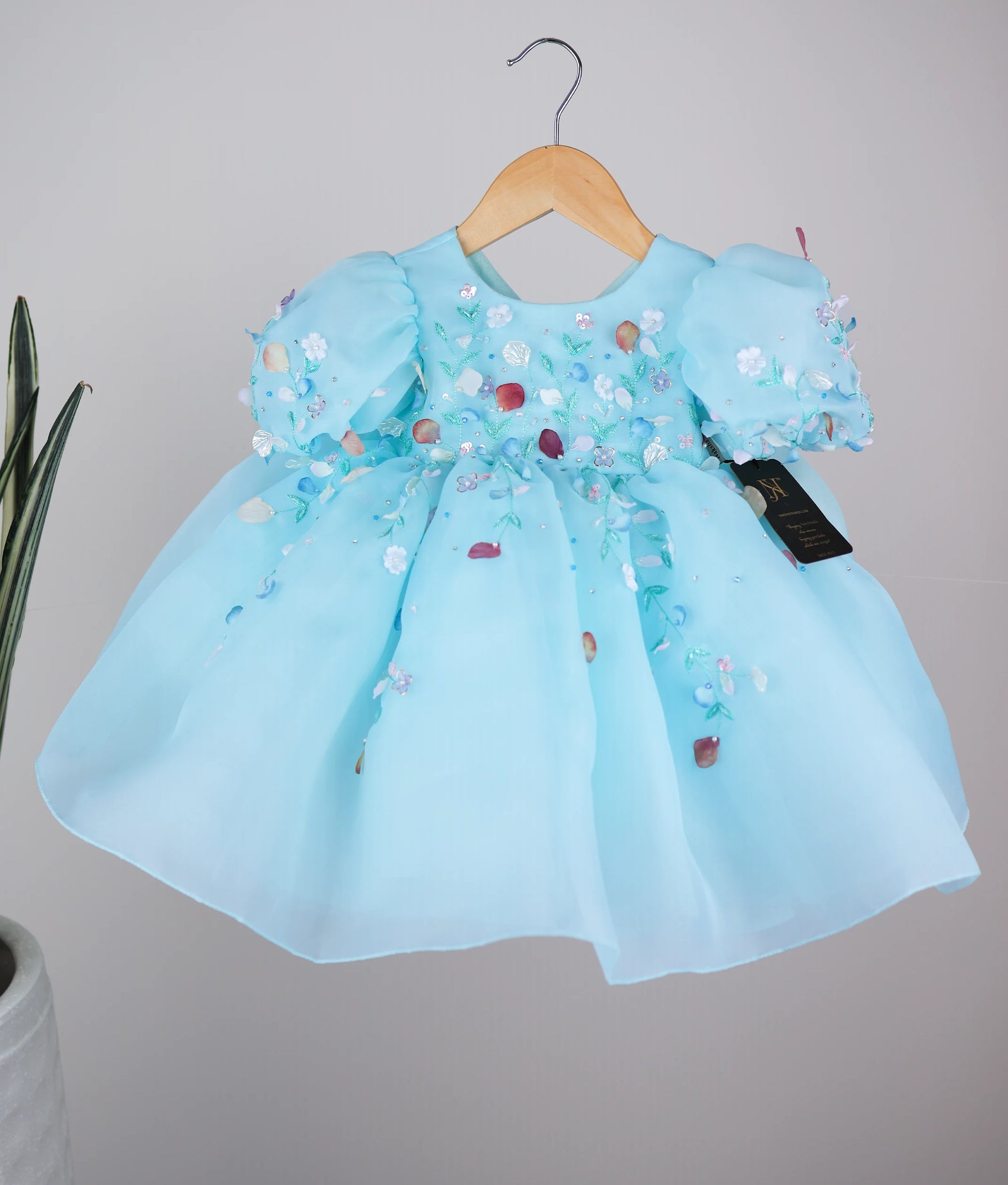 Blue frock with puff sleeves and floral handwork, displayed on a hanger.