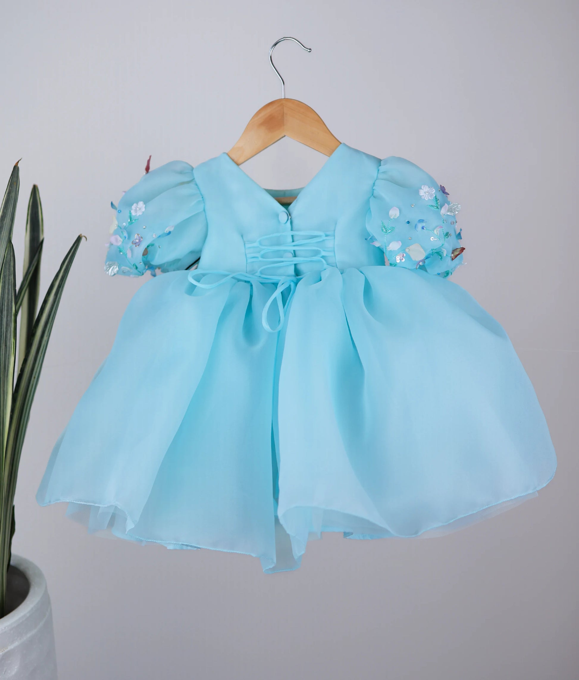 Back view of an blue frock displayed on a hanger.