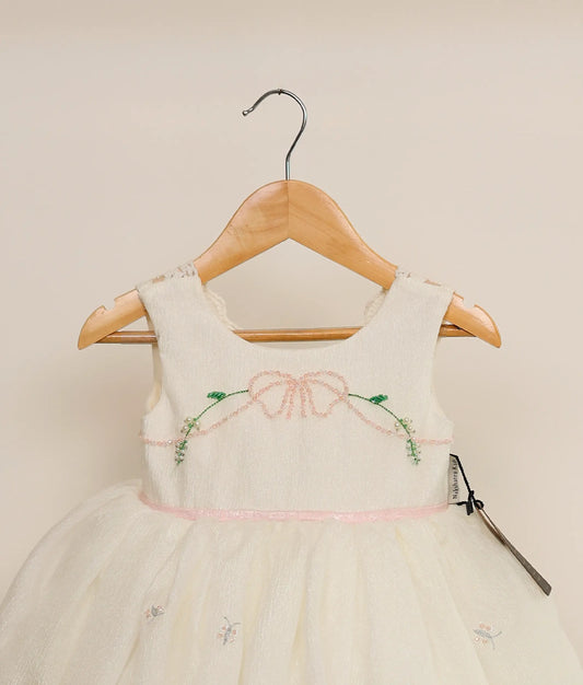 Close view of a crushed organza floral handwork birthday dress against plain background